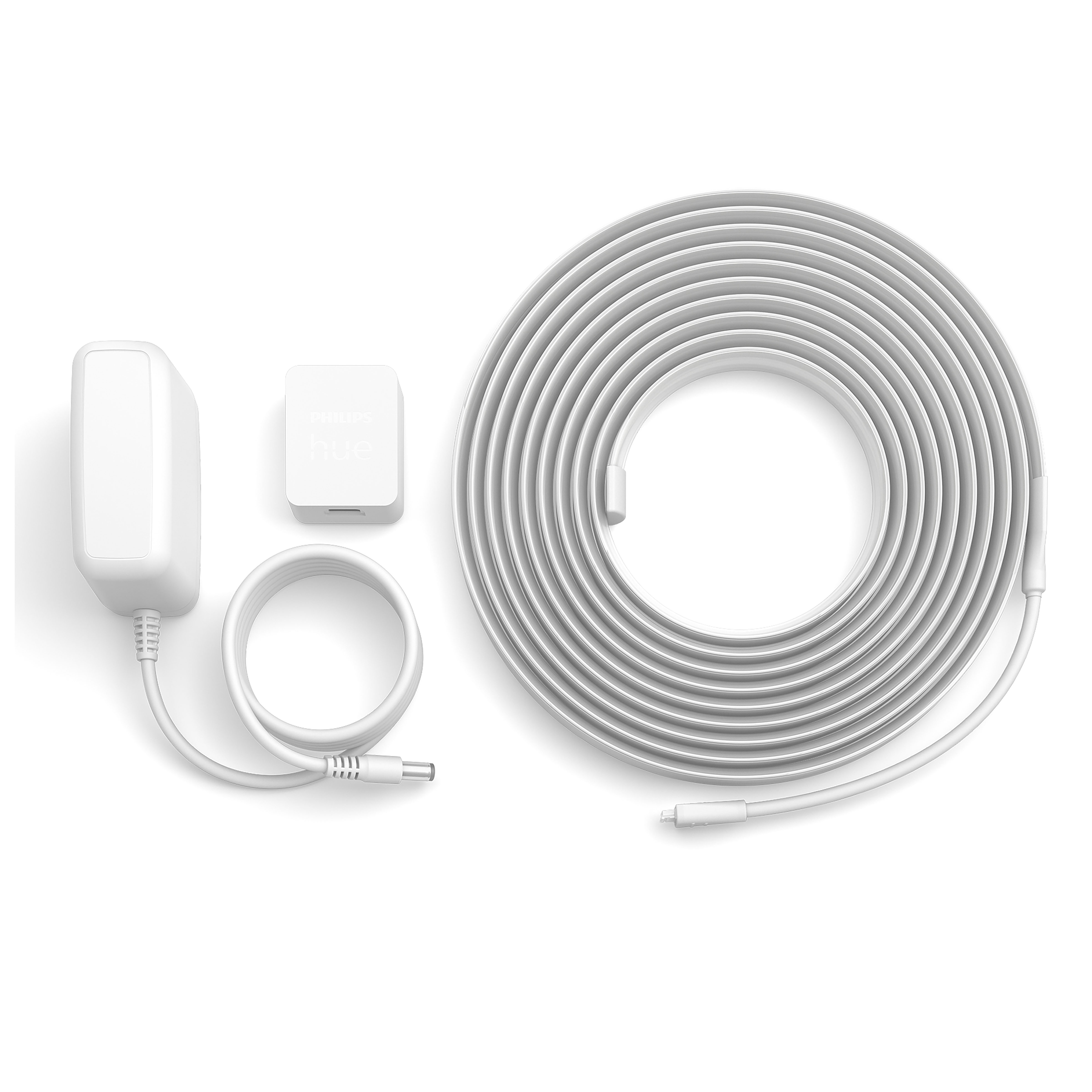 Białe elementy paska świetlnego: zasilacz, skrzynka sterownicza i zwinięty pasek świetlny, wszystko na białej powierzchni.