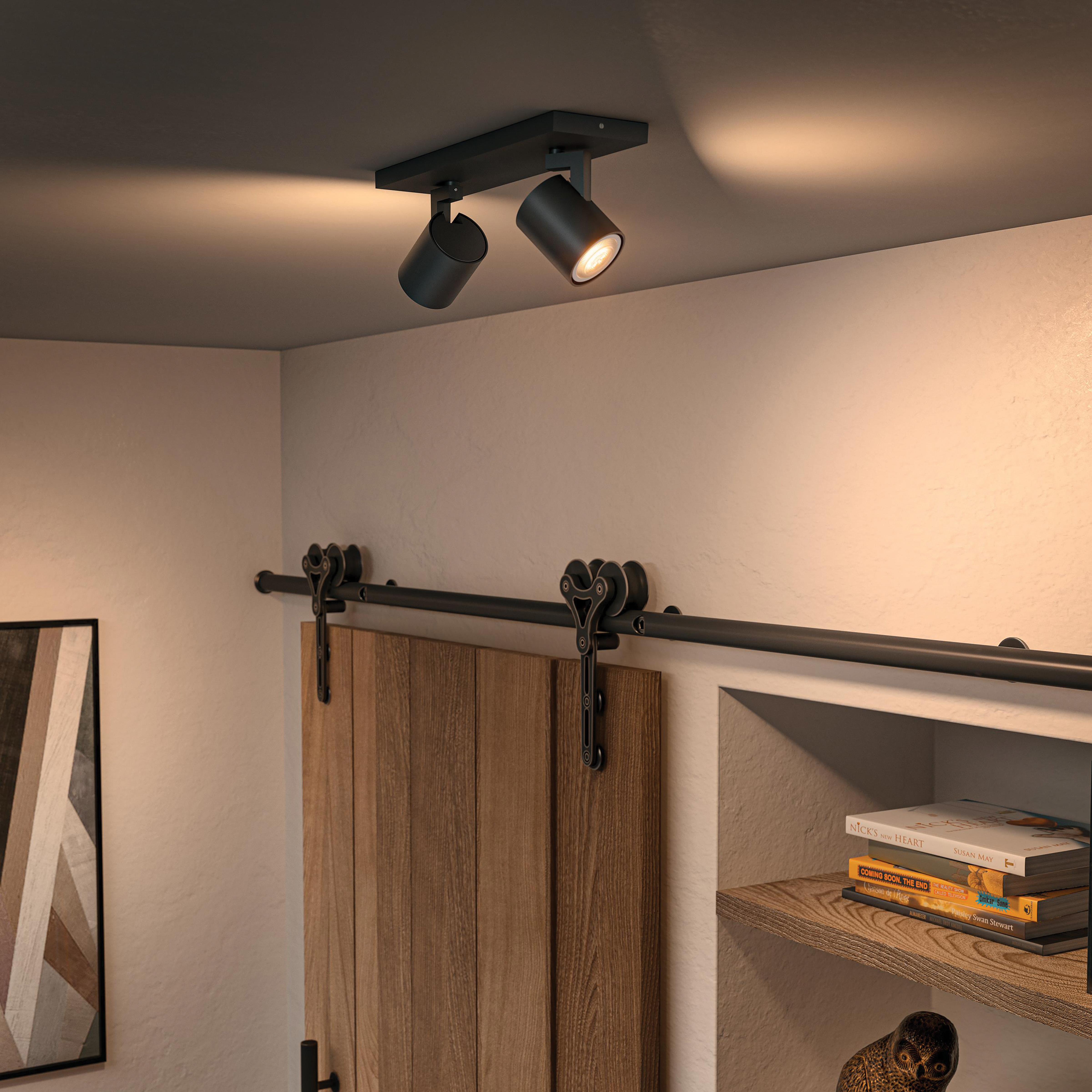 Twee zwarte spots in een kamer met houten deur en plank met items.