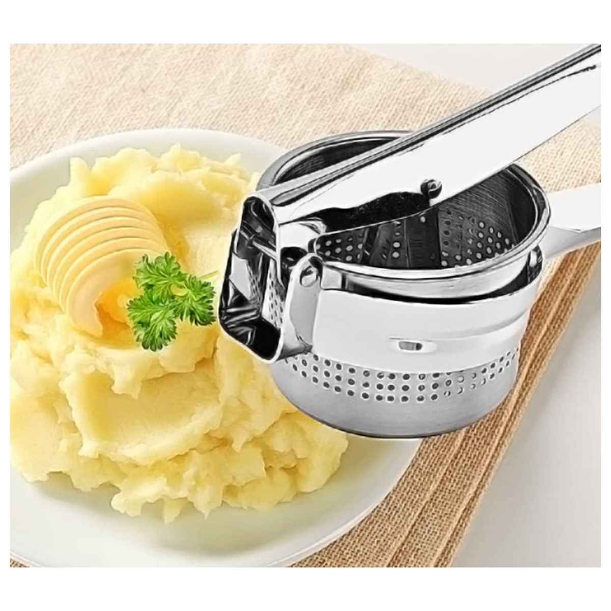 Kartoffelbrei auf einem Teller mit Butter und Petersilie. Neben den Kartoffeln befindet sich eine Kartoffelpresse.