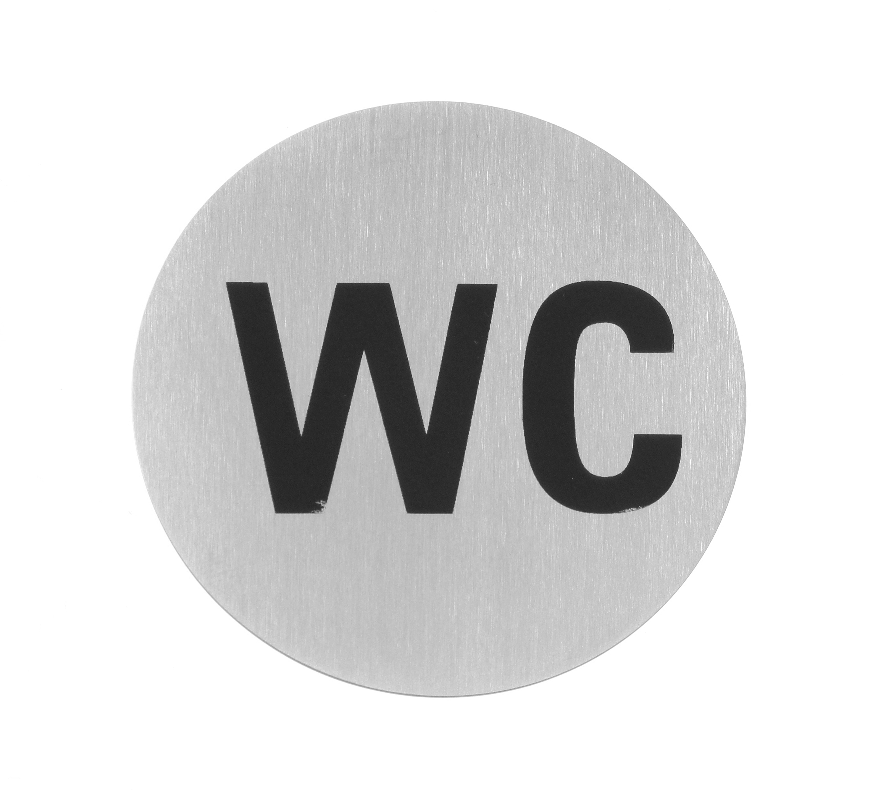 Un cartello rotondo in metallo spazzolato con lettere WC nere, su sfondo bianco.
