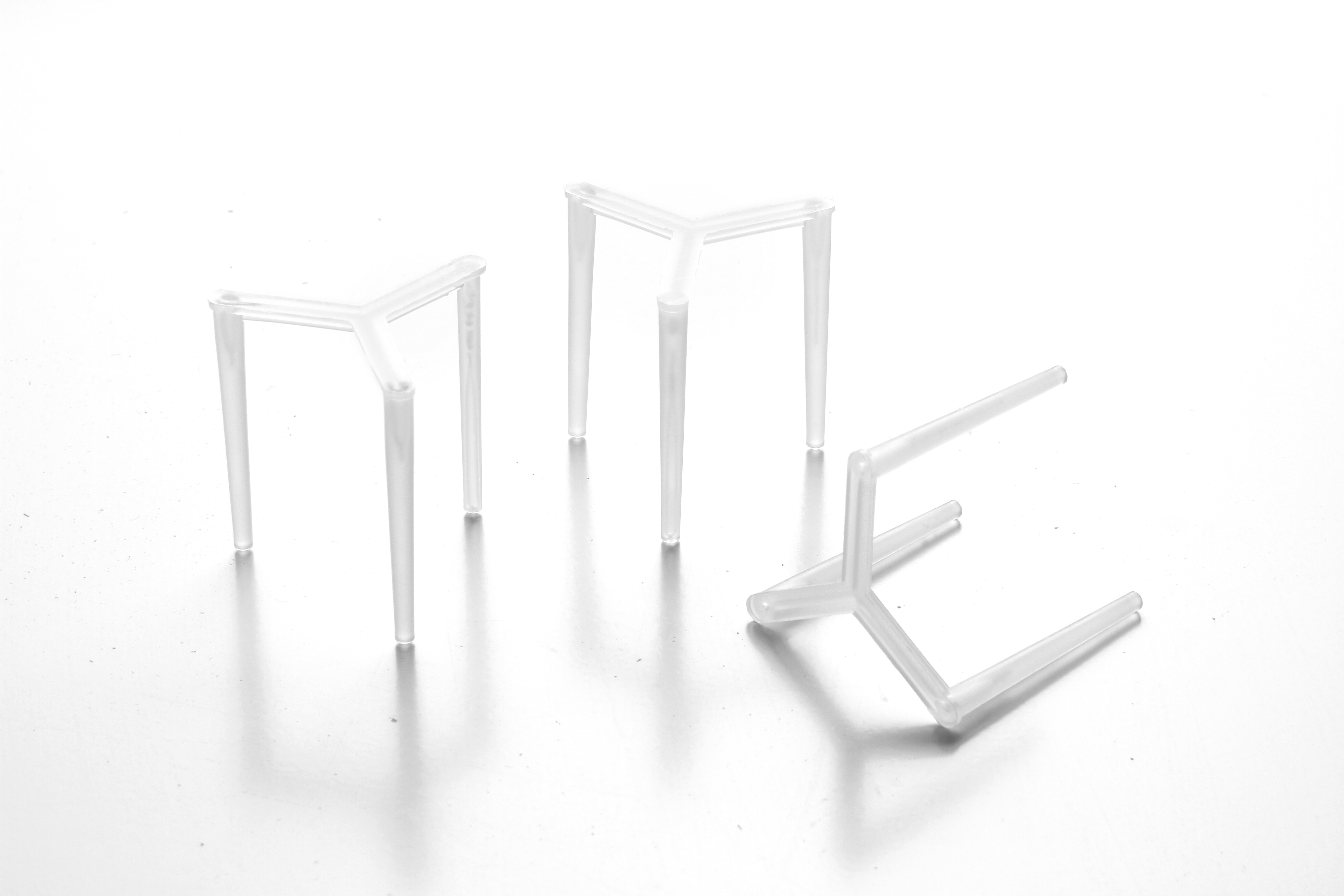 Tre supporti trasparenti in plastica a forma di Y. Sono su una superficie bianca.