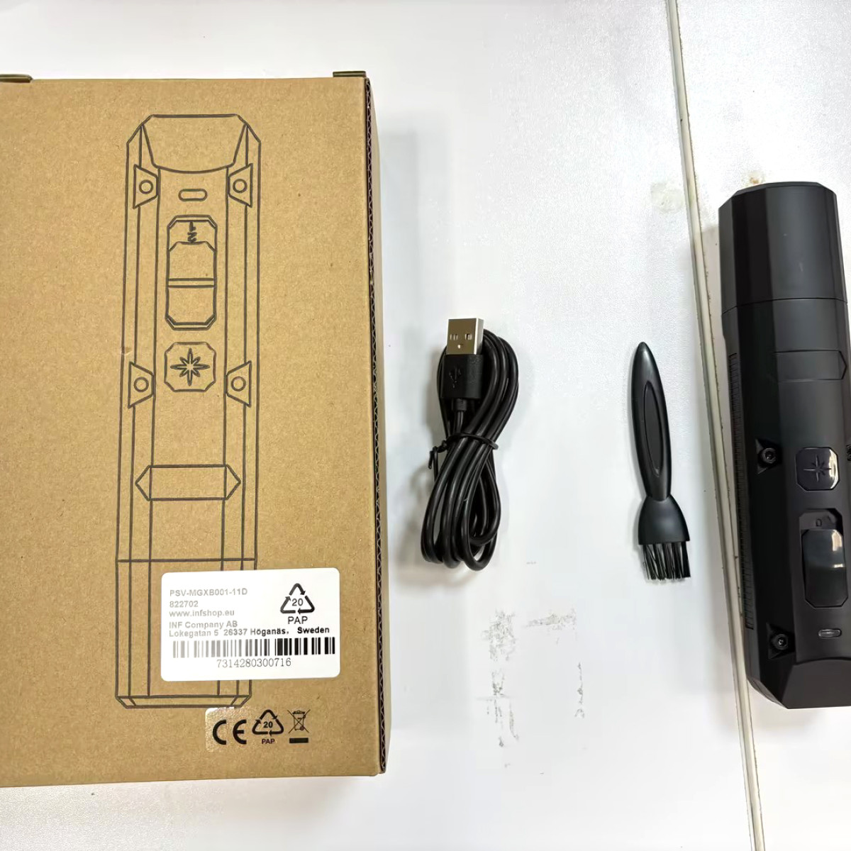 Brązowe pudełko z urządzeniem, kablem USB, szczotką i innym urządzeniem. Wszystko w kolorze czarnym.