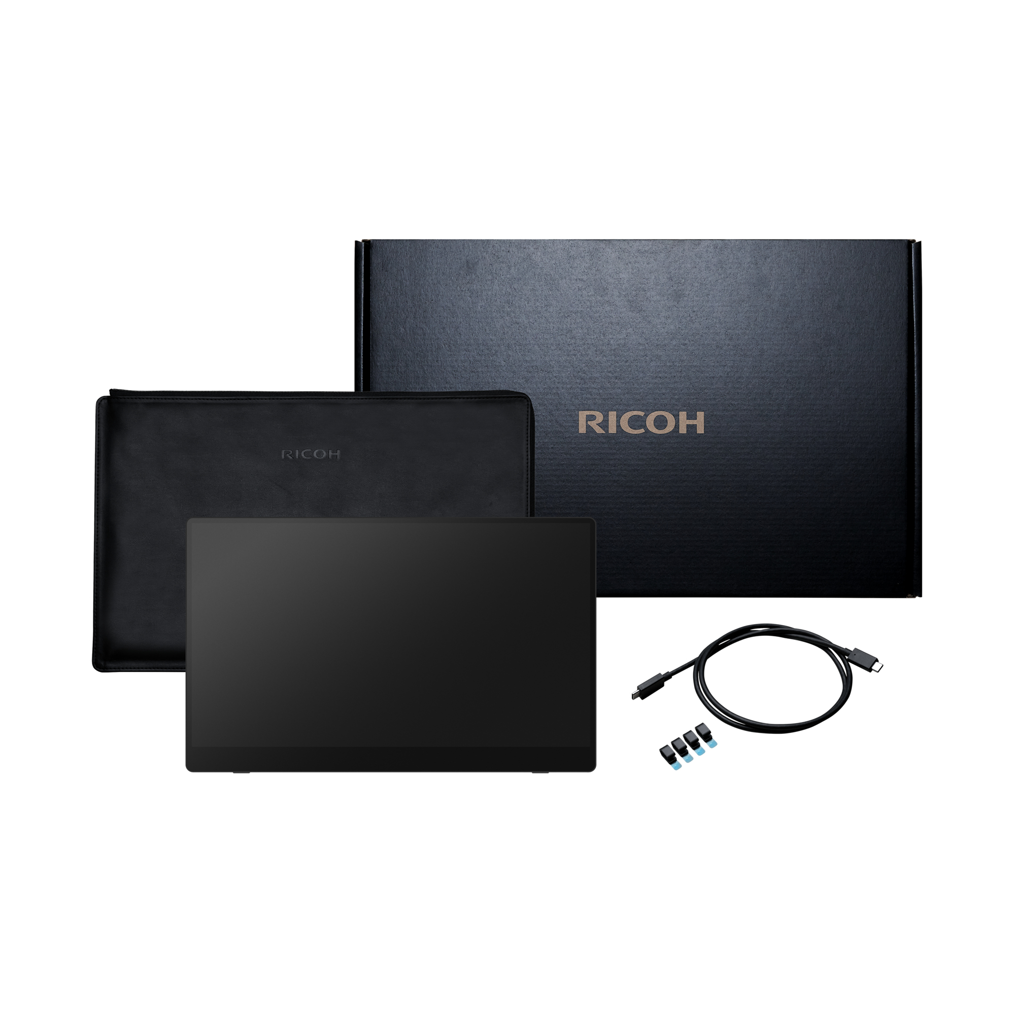 Monitor negro con accesorios: caja, funda, cable y adaptadores. La marca RICOH es visible.
