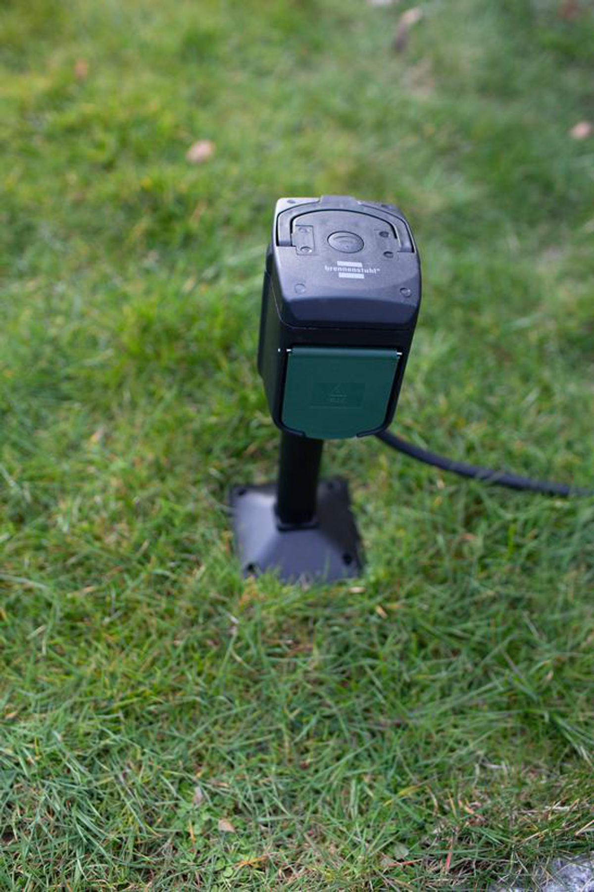 Presa esterna nera su erba verde. Colore scuro. Supporto nero.