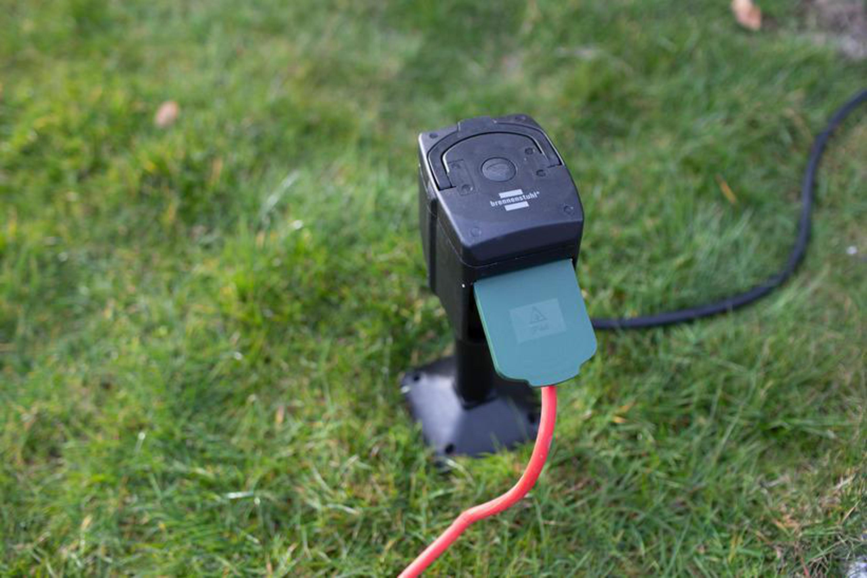 Presa nera e spina verde su erba verde, con cavo rosso.