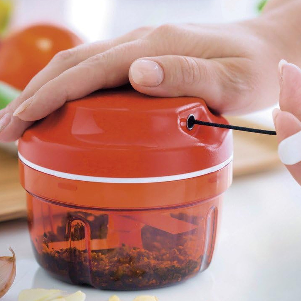 Hand bedient einen roten Zerkleinerer. Der untere Teil ist mit gehacktem Essen gefüllt.