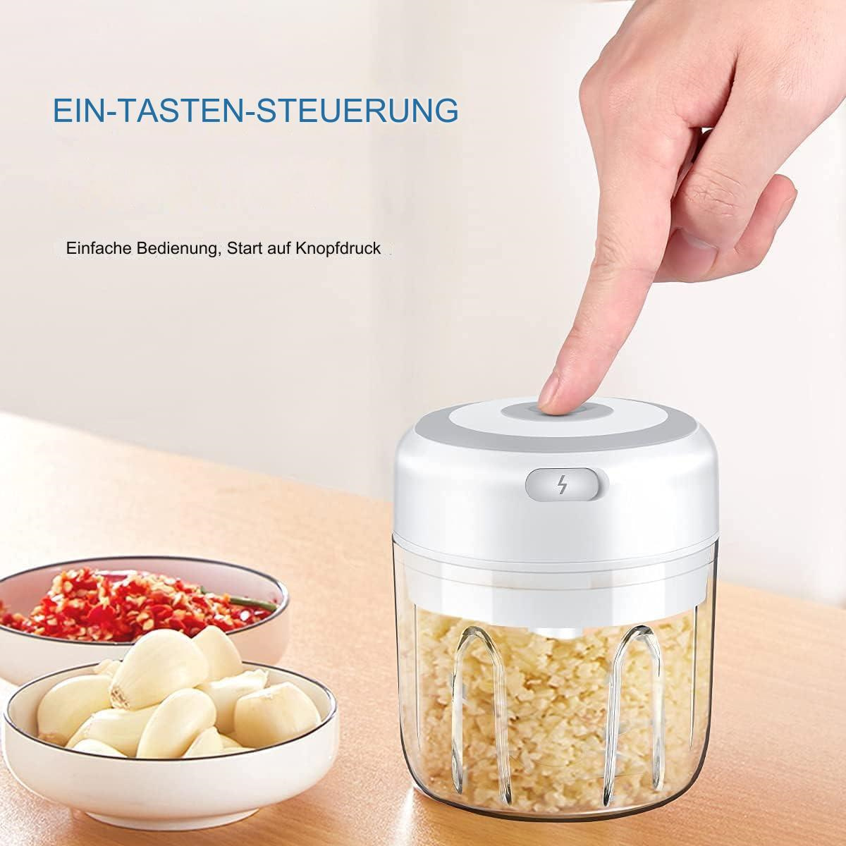 Eine Person, die den Knopf auf einem weißen und klaren Zerkleinerer drückt. Schalen mit Zutaten.