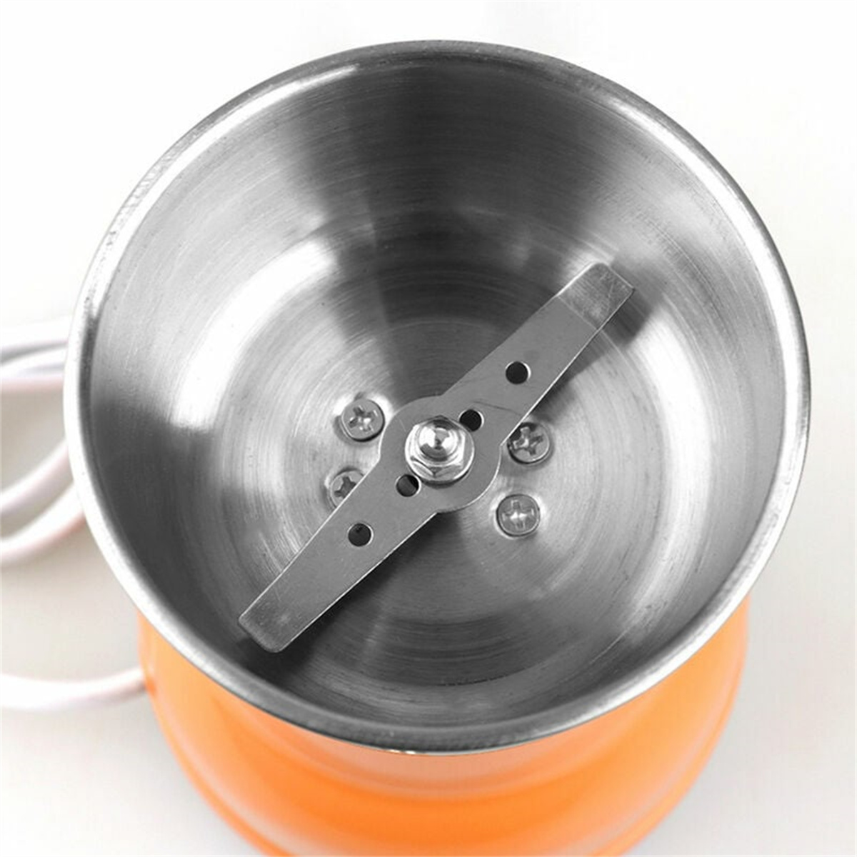Oranger elektrischer Grinder. Edelstahl-Innenraum. Klingen sichtbar.