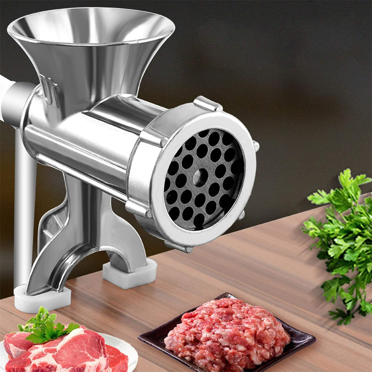 Fleischwolf, mit Hackfleisch und Fleischstücken sowie Petersilie auf einer Holzoberfläche.