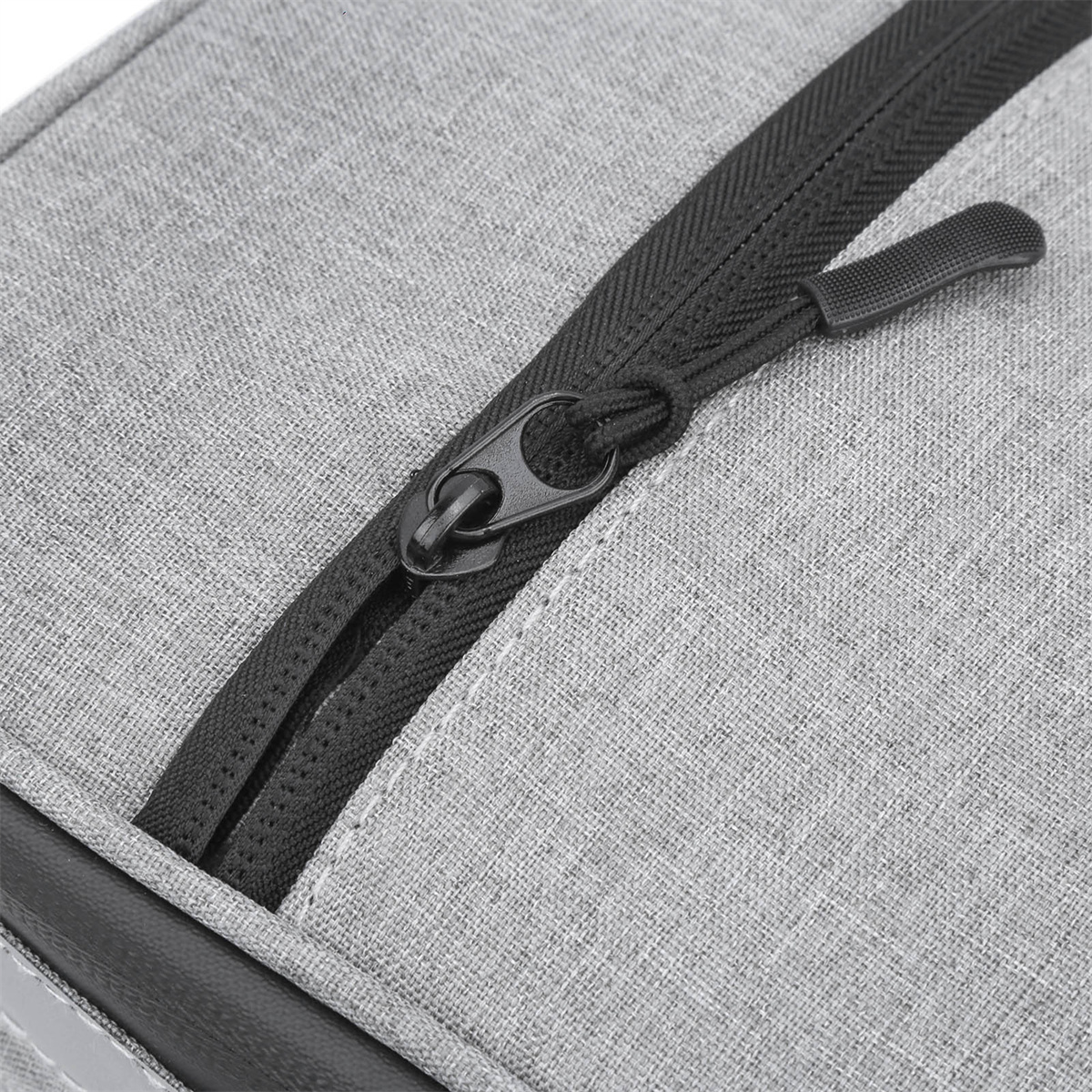 Nahaufnahme einer grauen Stofftasche mit einem schwarzen Reißverschluss.