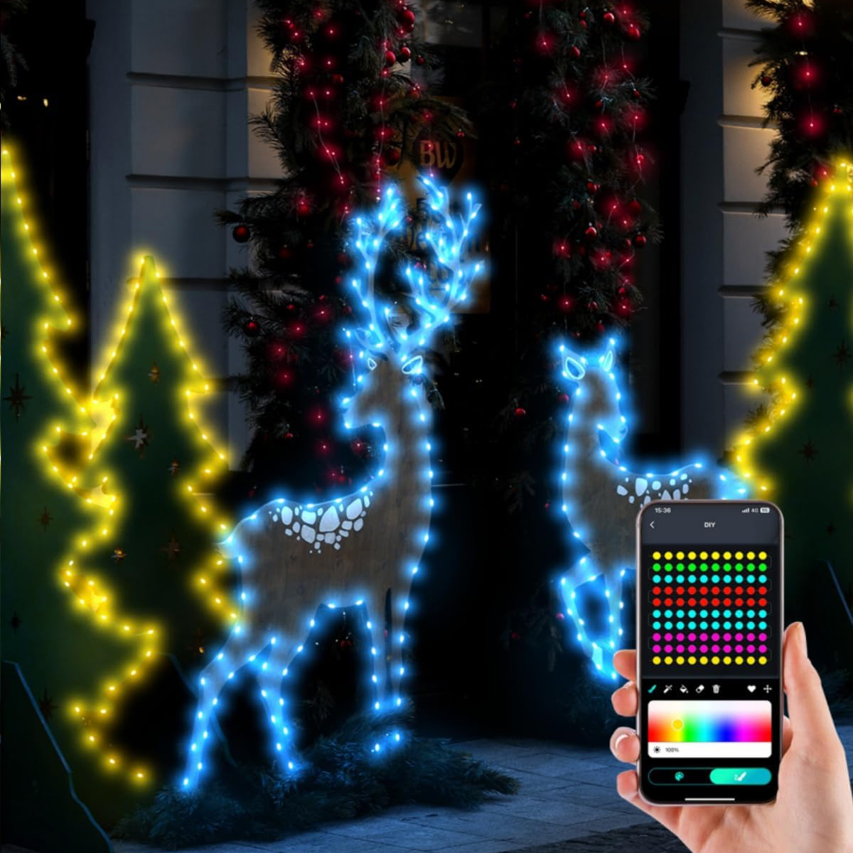 Zwei Hirsch-Lichtfiguren vor einem Gebäude. Eine Person hält ein Telefon, das die Lichter steuert.