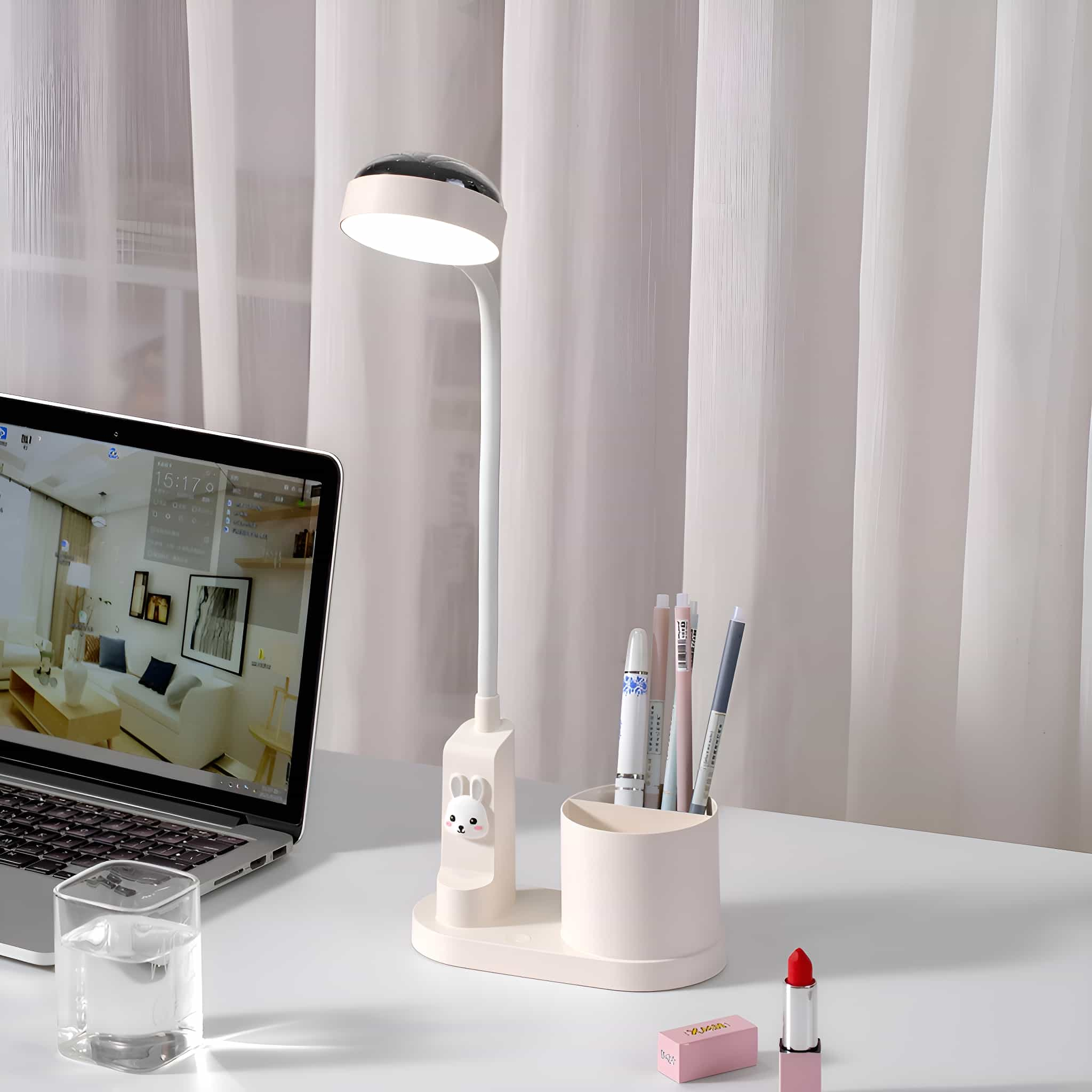 Eine weiße Schreibtischlampe mit Stifthalter, Stiften und Lippenstift auf einem Schreibtisch.