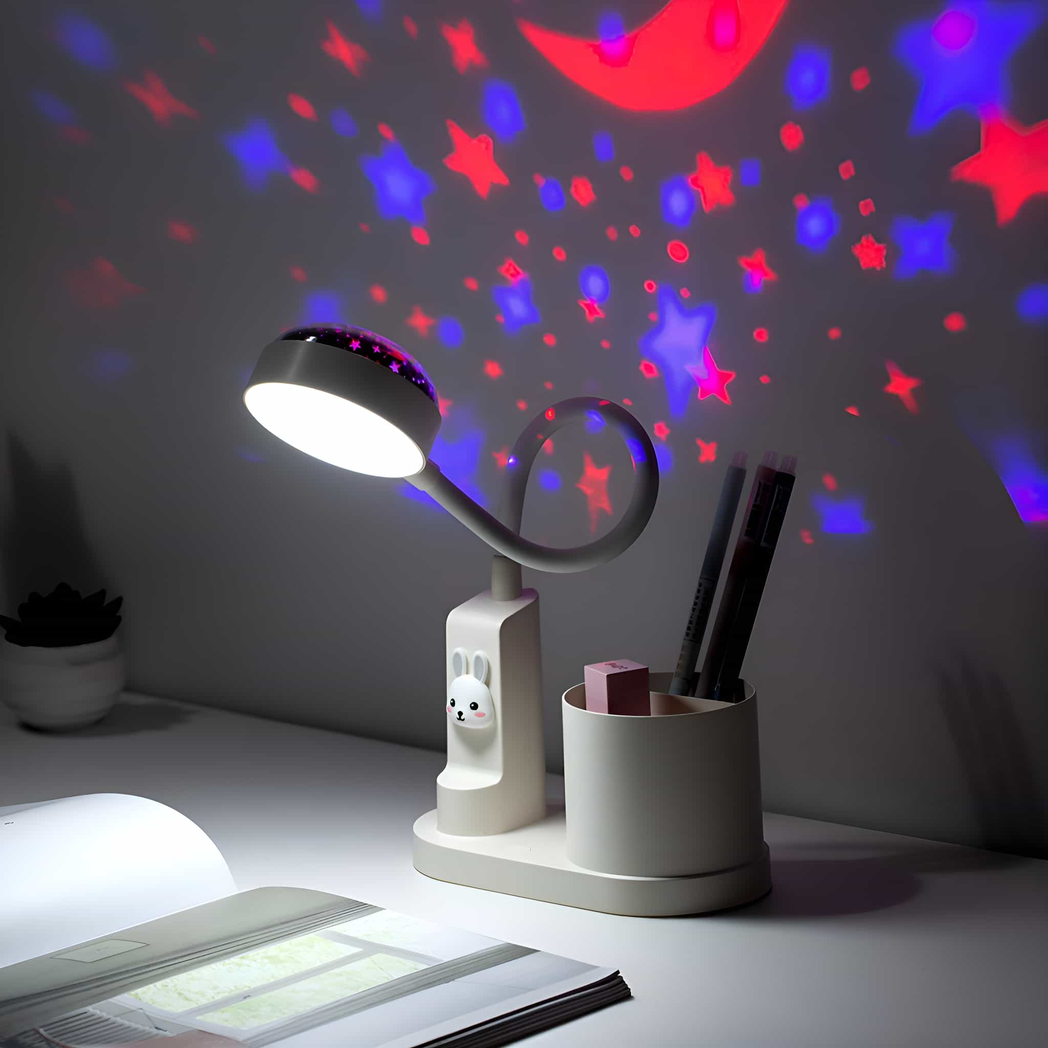 Schreibtischlampe mit Kaninchen-Detail auf dem Sockel, projiziert Sterne und Mond. Stifthalter und Artikel sind vorhanden.