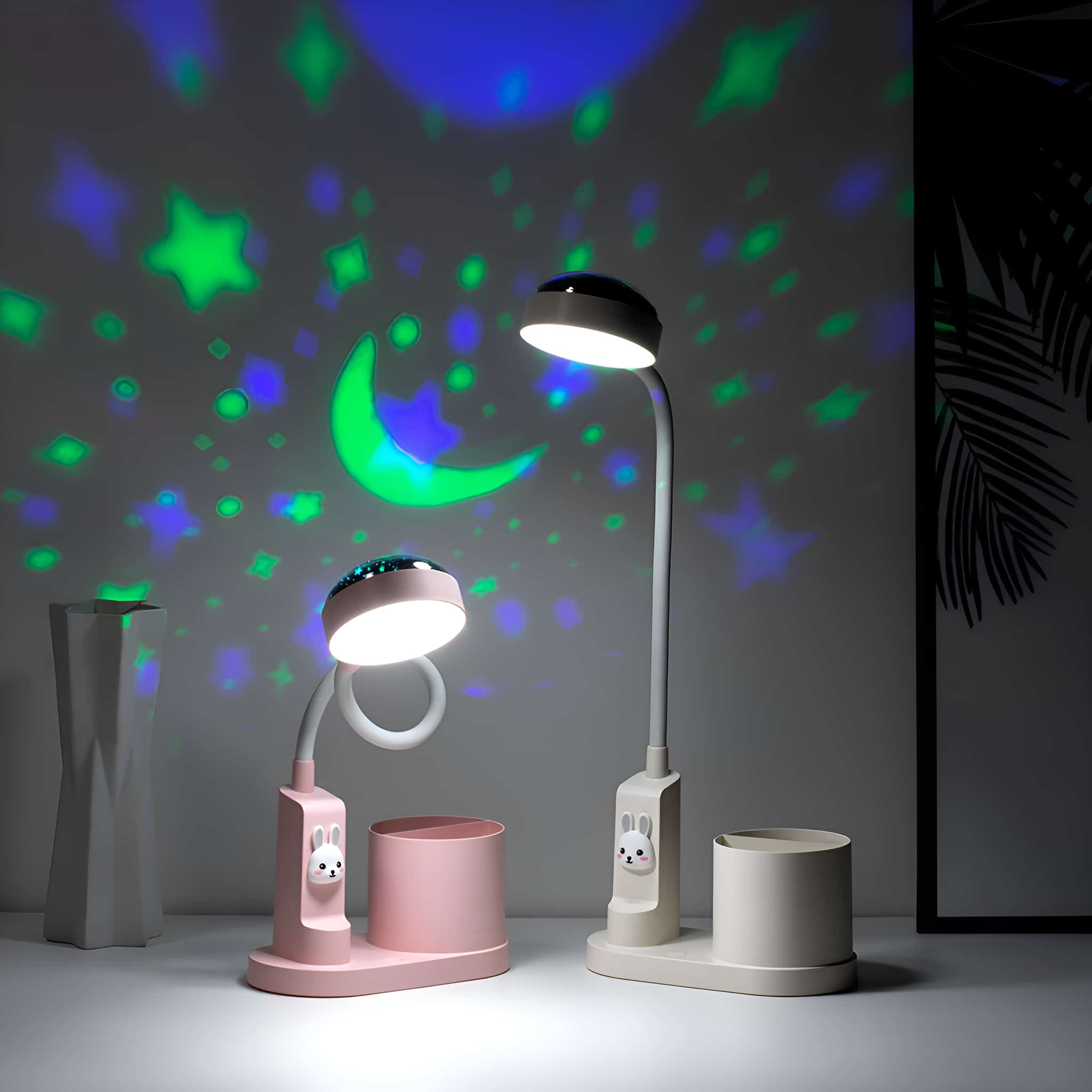 Zwei Schreibtischlampen mit Projektionseffekten. Eine rosa, eine weiße. Sterne und Mond werden an die Wand projiziert.
