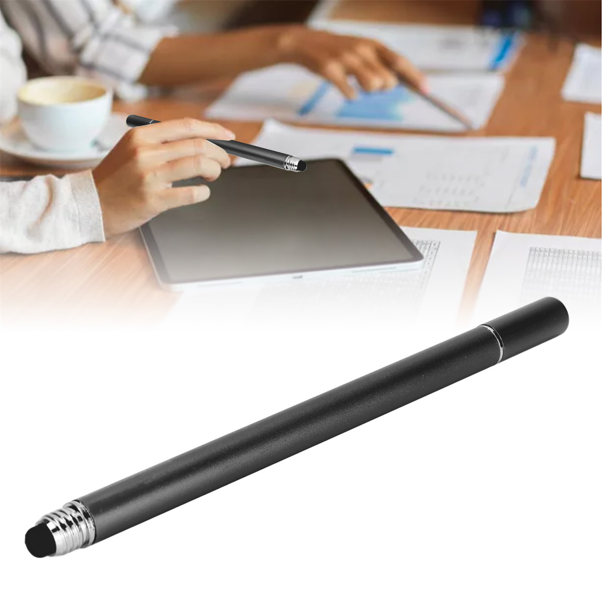 Schwarzer Stift auf einem Tisch mit Tablet und Papieren. Eine andere Hand hält Stift.