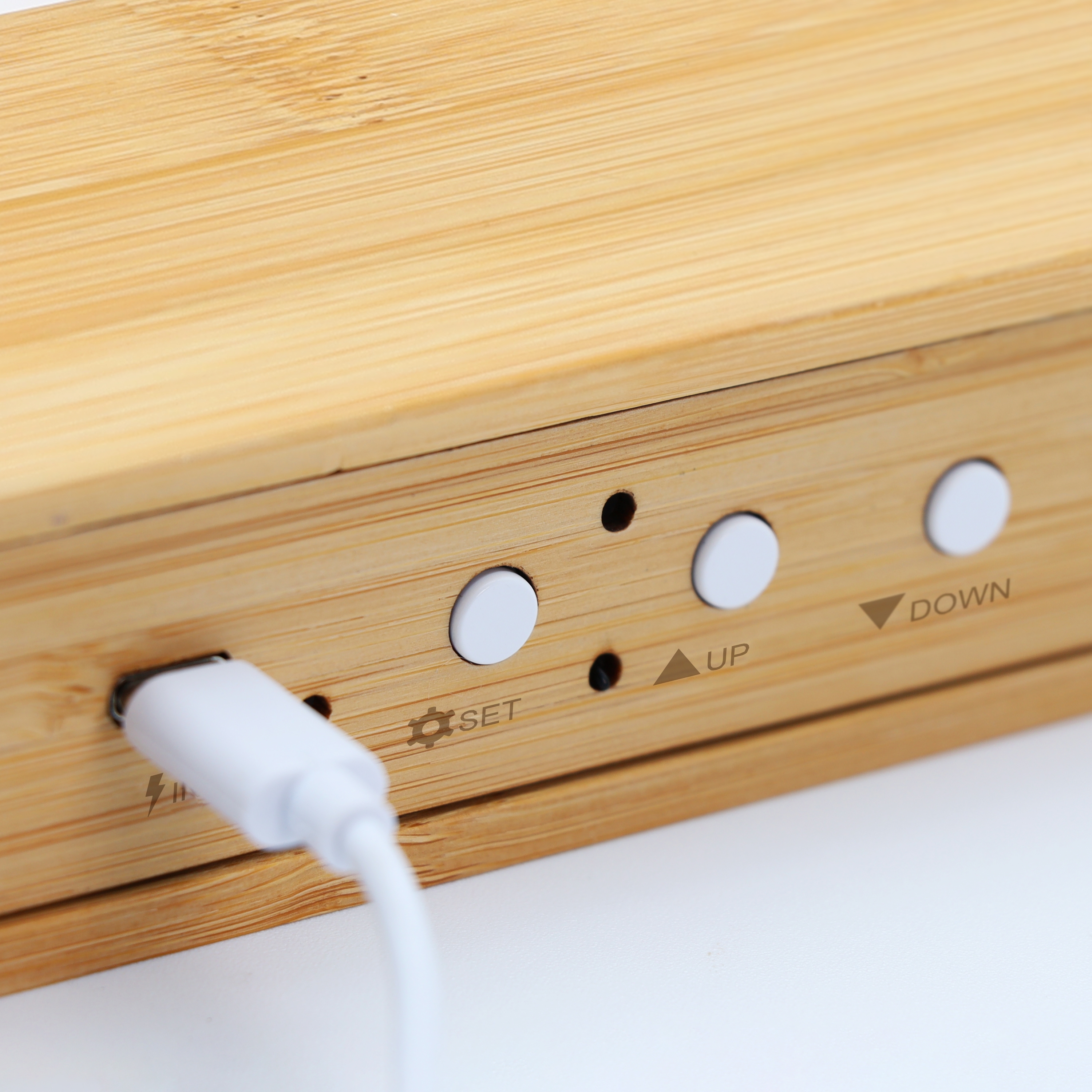 Primer plano de un dispositivo de madera con botones y un puerto de carga.