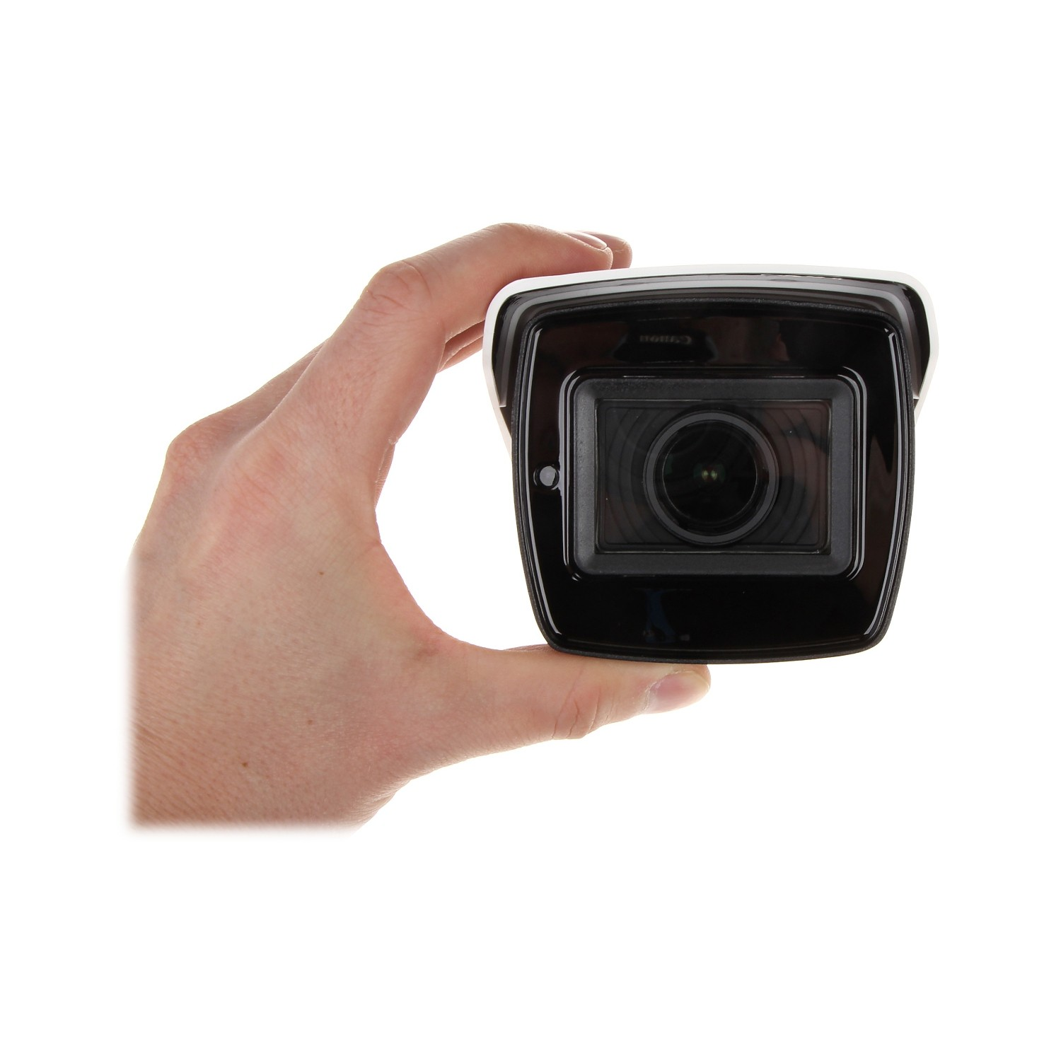 Ręka trzymająca czarną kamerę bezpieczeństwa. Białe tło.