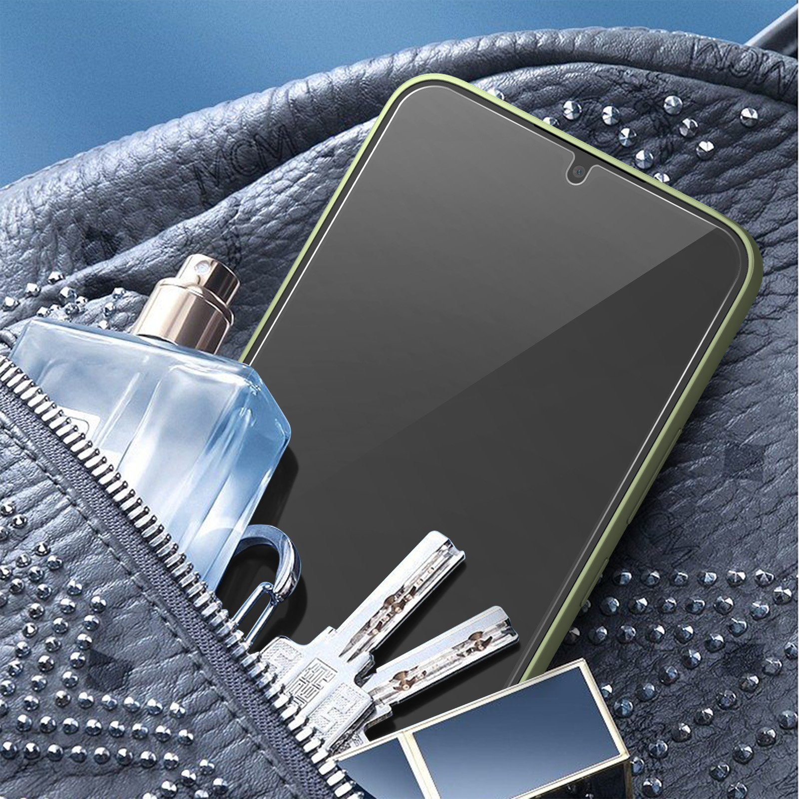 Un telefono con protezione schermo, chiavi, profumo e un astuccio per il trucco in una borsa grigia borchiata.