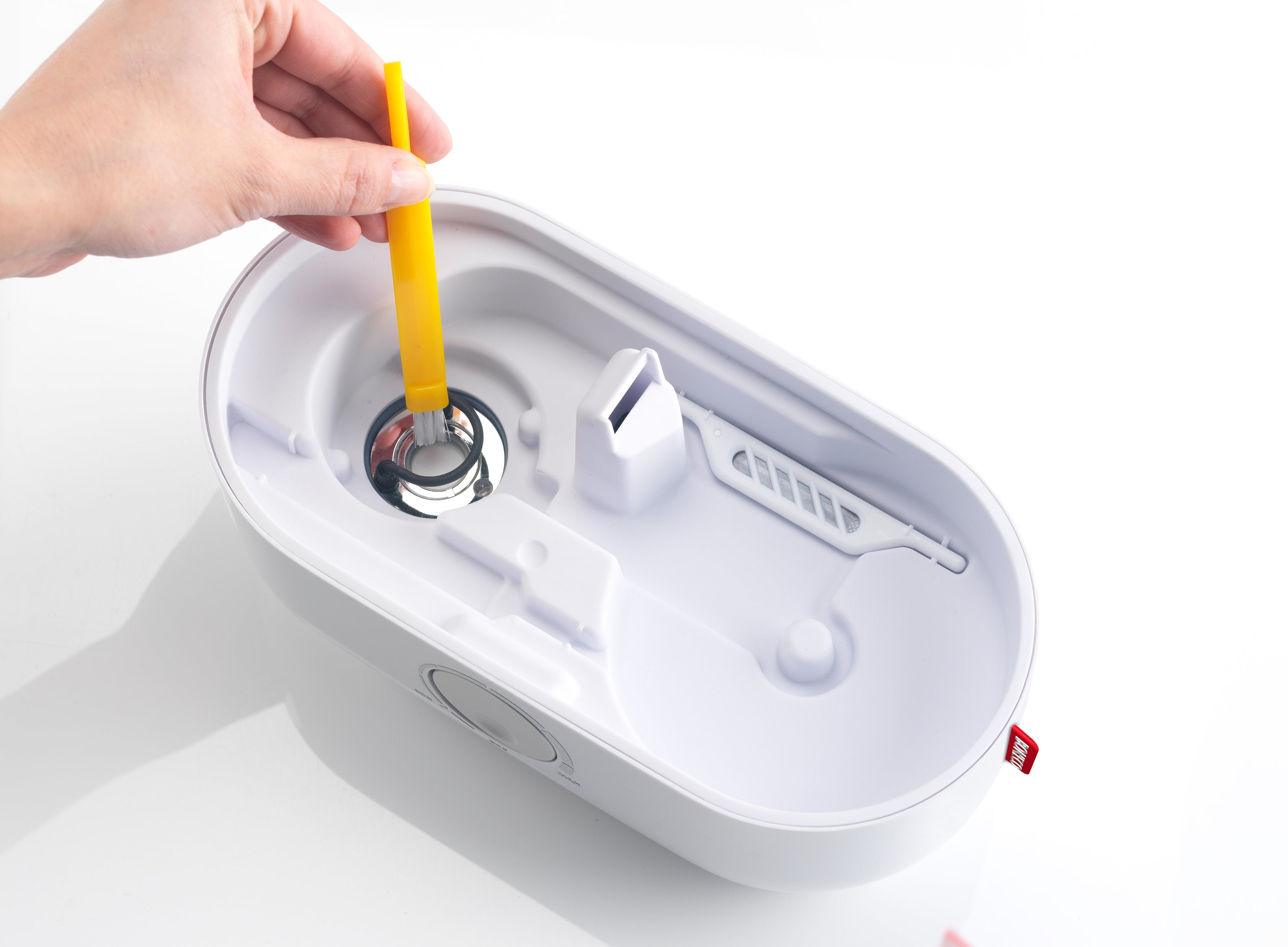 Una mano con uno strumento giallo all'interno di un umidificatore bianco.