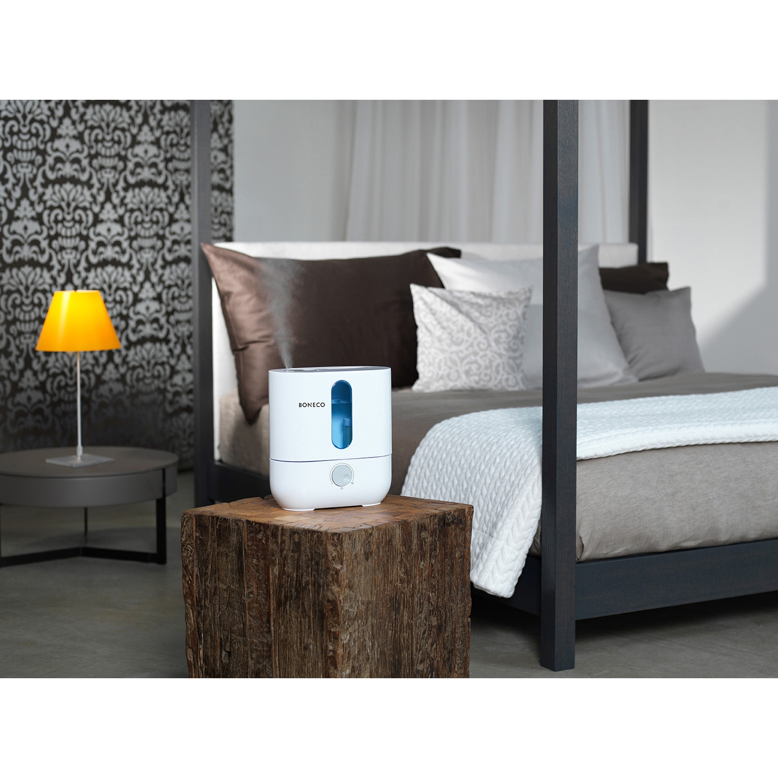 Umidificatore bianco su blocco di legno, in camera da letto, letto sullo sfondo.