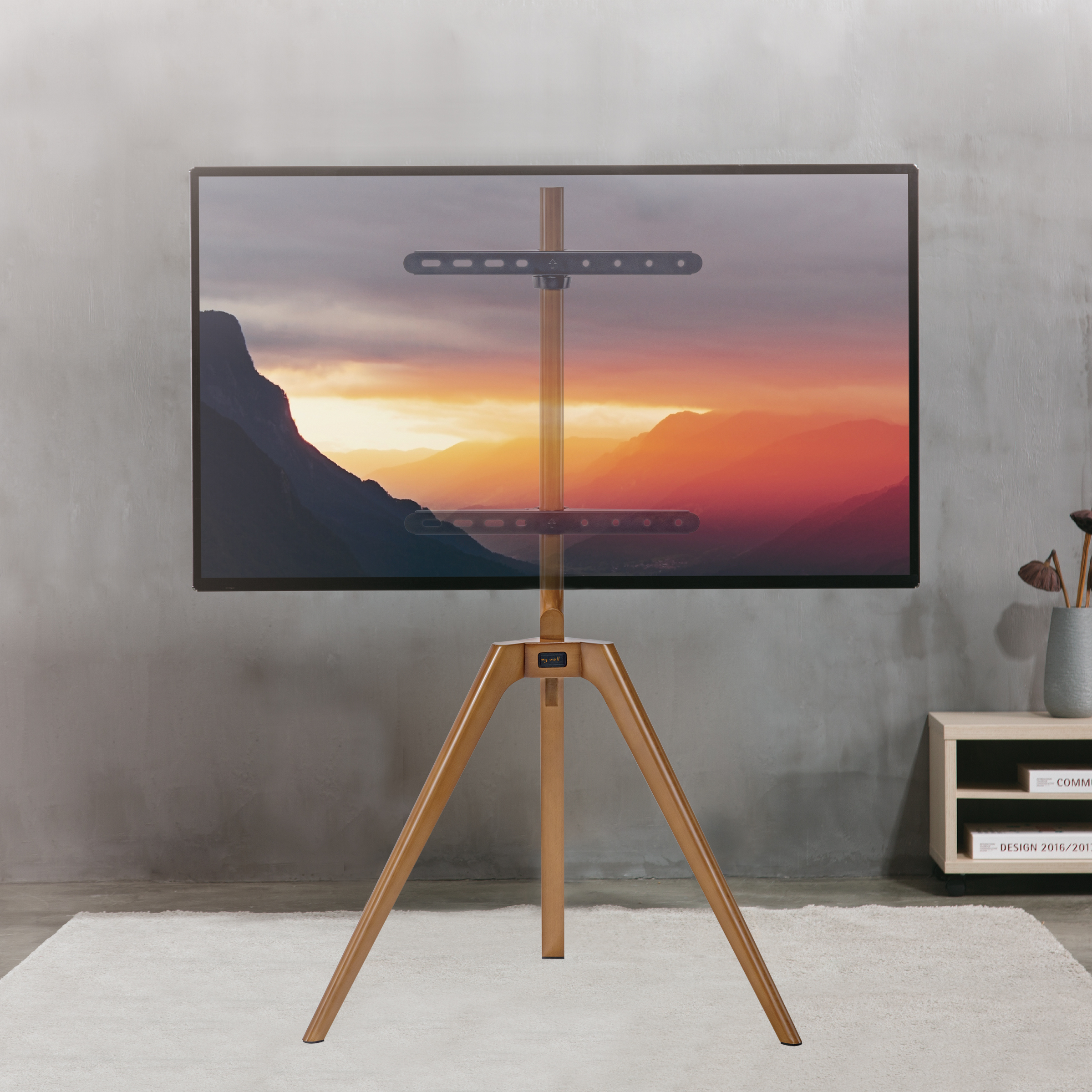 Fernseher auf Holzstativ, mit Sonnenuntergangslandschaft auf dem Bildschirm.