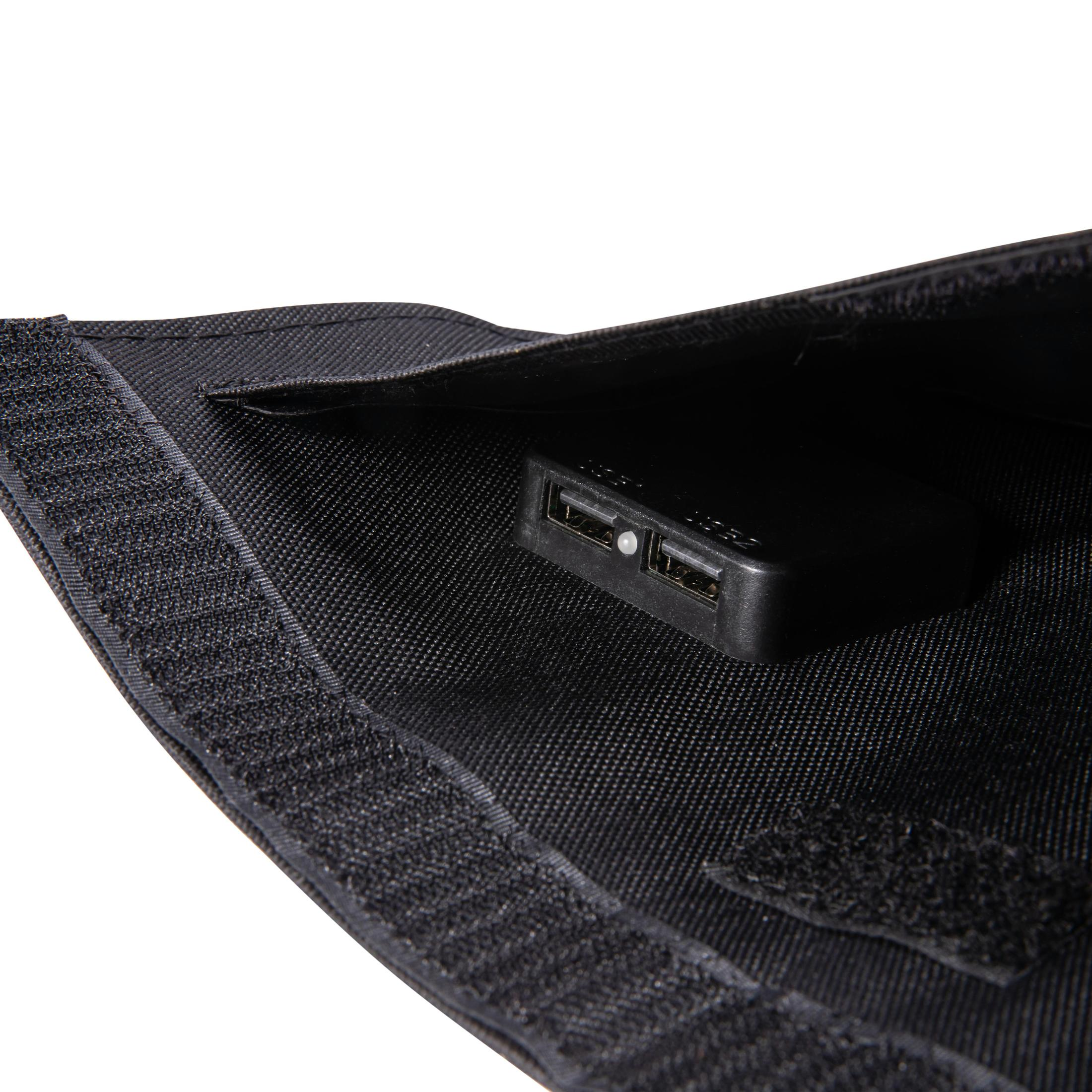 Czarna saszetka z czarną ładowarką USB w środku, widoczna przez otwór. Rzep jest przymocowany.