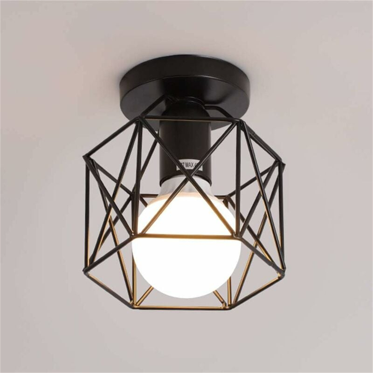 Eine moderne schwarze geometrische Lampenhalterung mit Glühbirne an einer weißen Decke.