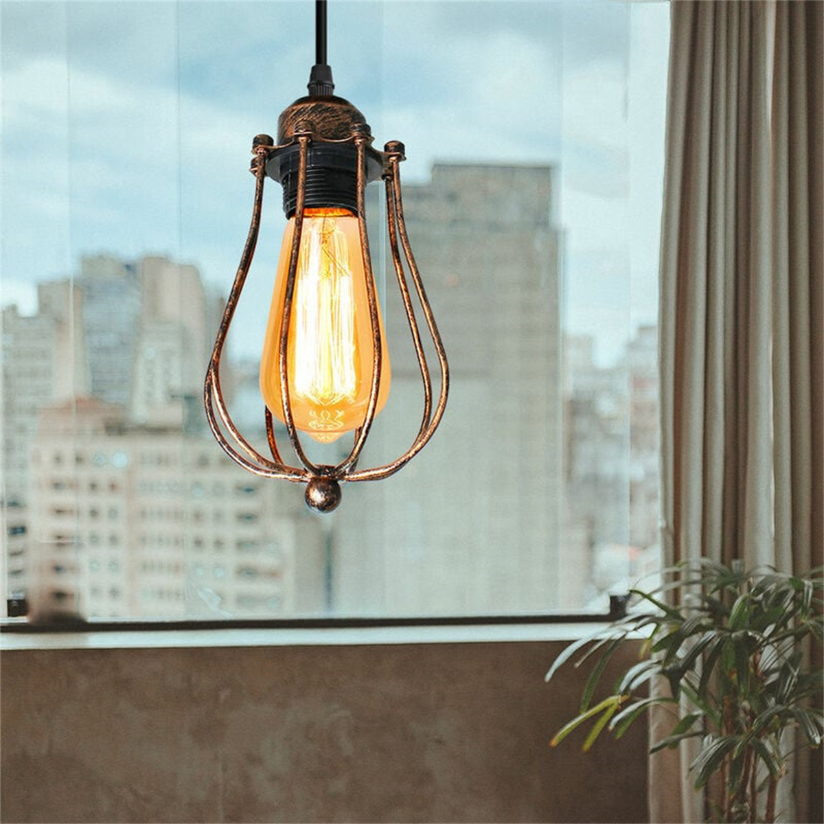 Eine Hängelampe im Vintage-Design, mit Edison-Glühbirne und Metallkäfig, vor verschwommenem Hintergrund.
