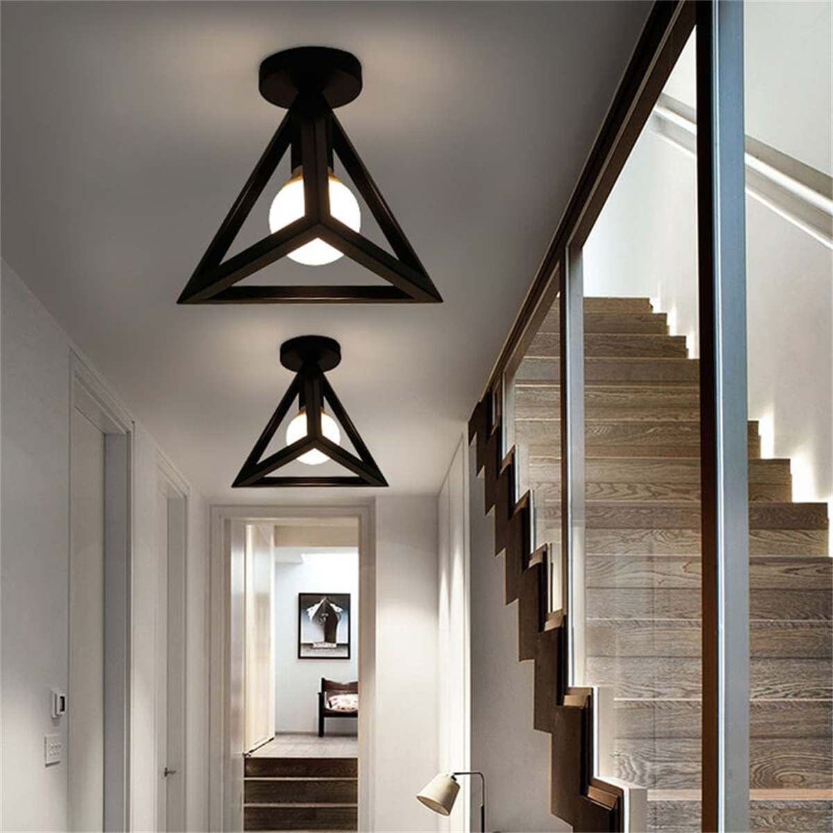 Flur mit zwei dreieckigen Leuchten. Treppe rechts, weiße Türen links. Warmes Licht von den Lampen.
