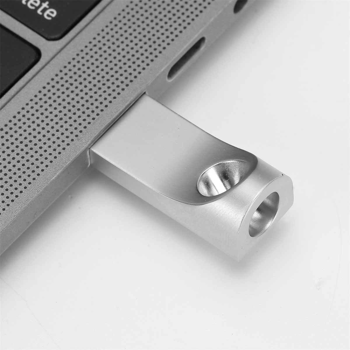 Silberner USB-Stick, der in einen Laptop eingesteckt ist. Weißer Hintergrund.