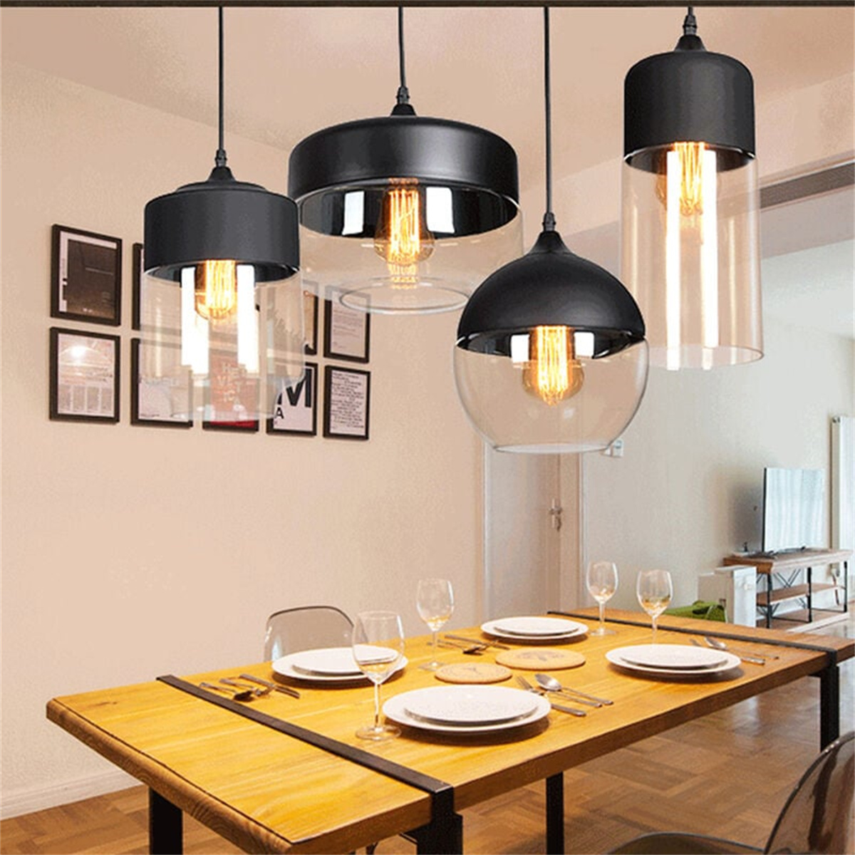 Esszimmer mit vier hängenden Pendelleuchten, einem Holztisch mit Tellern und vier Weingläsern.