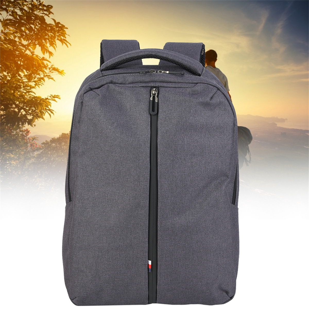 Grauer Rucksack mit schwarzem Reißverschluss und ein Mann im Hintergrund in der Natur.