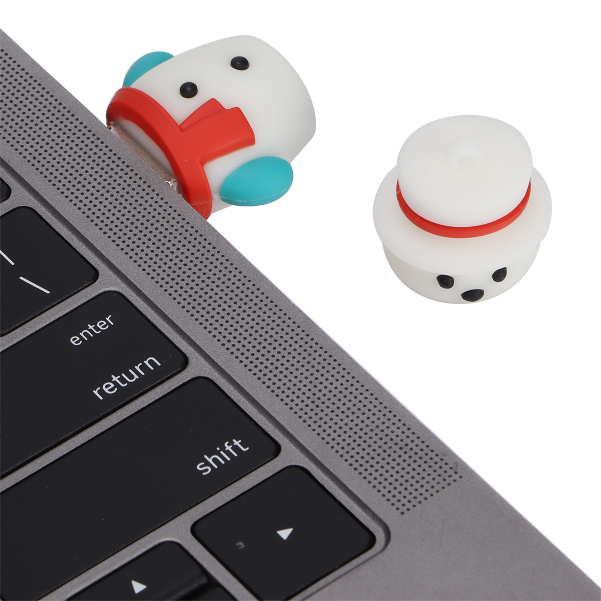 Zwei USB-Stecker in Schneemannform neben einer Laptop-Tastatur.