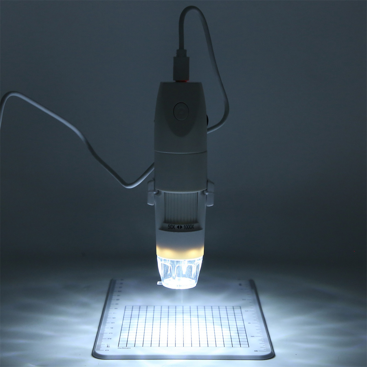 Ein weißes Mikroskop mit Licht leuchtet auf einer weißen Oberfläche. Auf der Oberfläche befindet sich ein Raster.