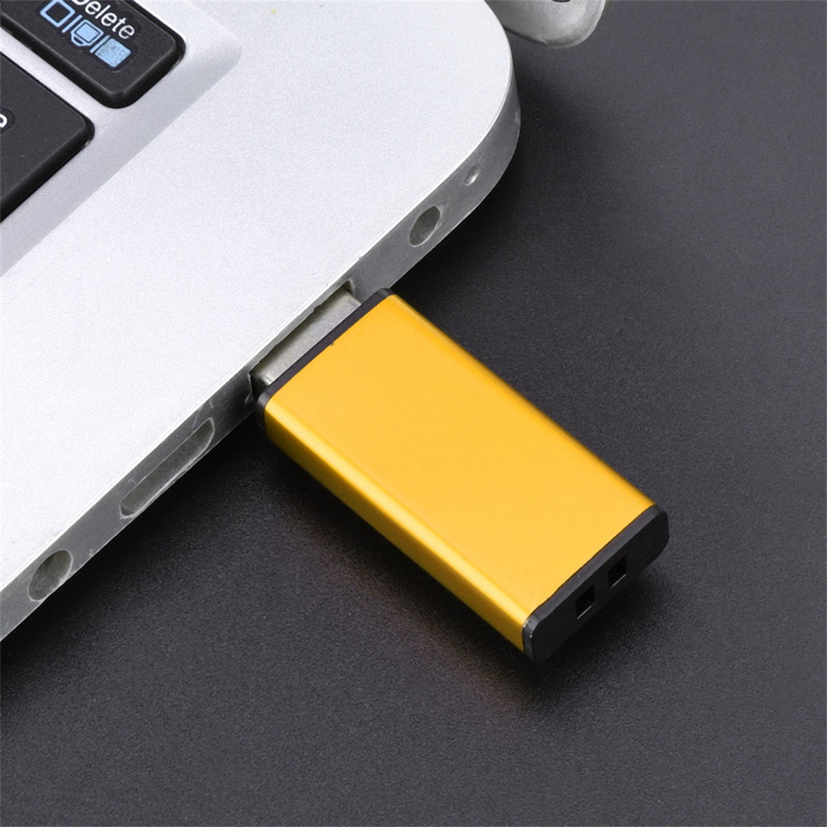 Goldener USB-Stick, der in einen Laptop eingesetzt ist, schwarzer Hintergrund.