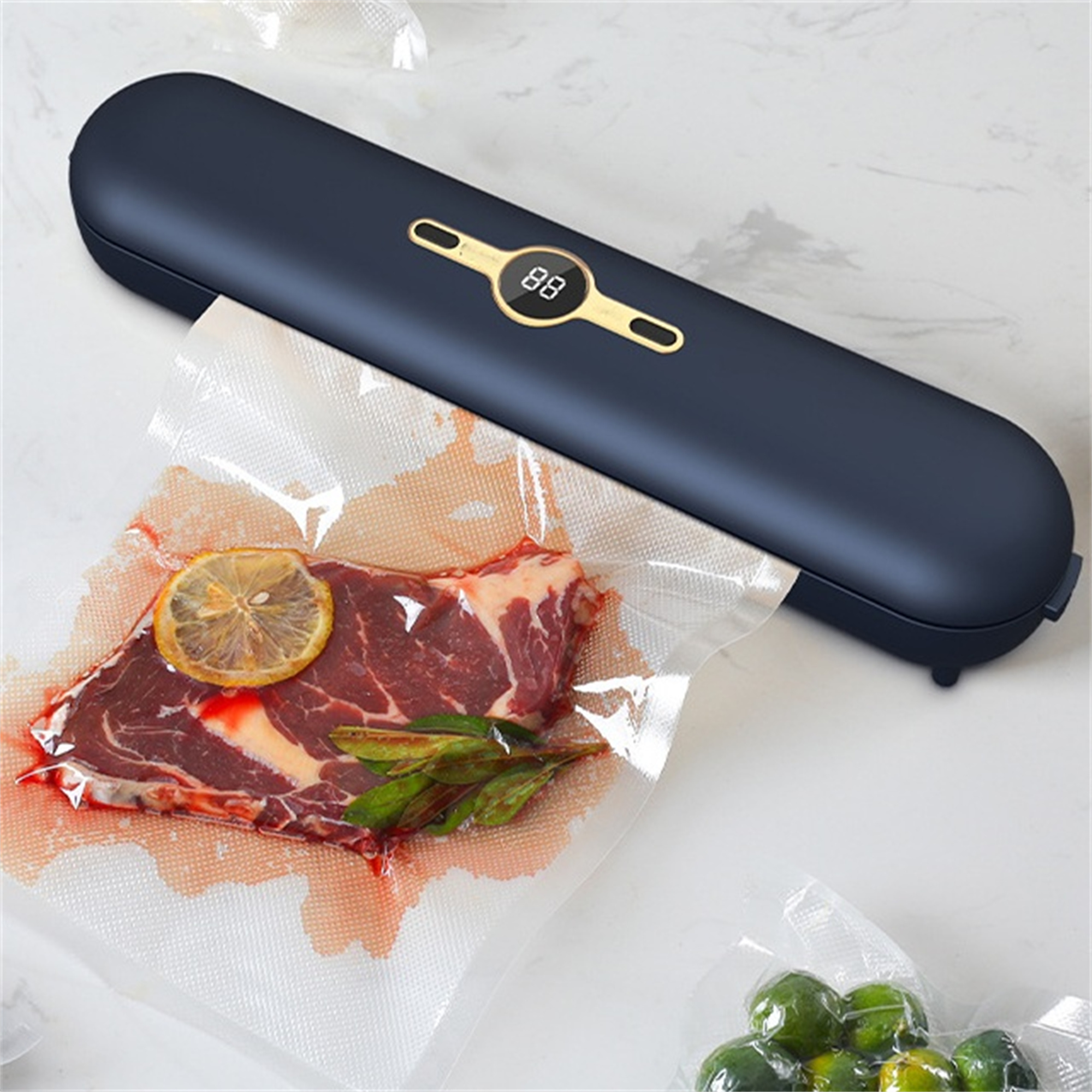 Ein Vakuumierer mit einem Steak in einem Beutel. Eine Zitronenscheibe liegt auf dem Steak. Weiße Theke.
