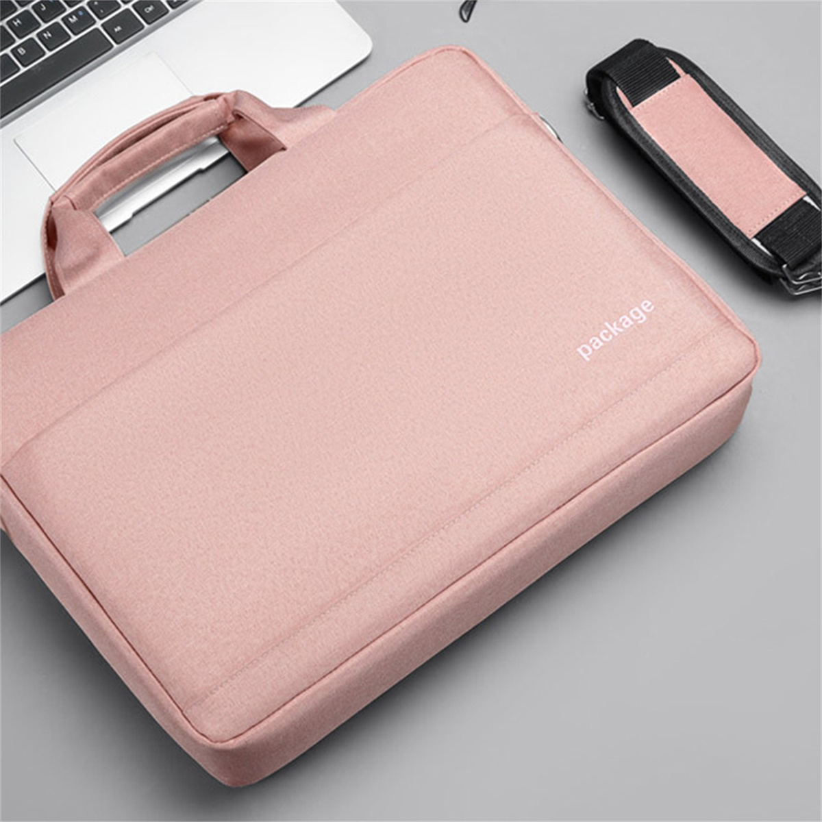 Rosa Laptoptasche mit Griff, Schulterriemen und dem Aufdruck 'package'. Graue Oberfläche.