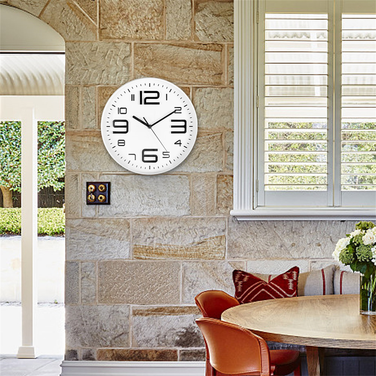 Eine weiße Uhr an einer Steinmauer. Die Uhr zeigt die Uhrzeit an, und die Umgebung sieht wie ein Haus aus.