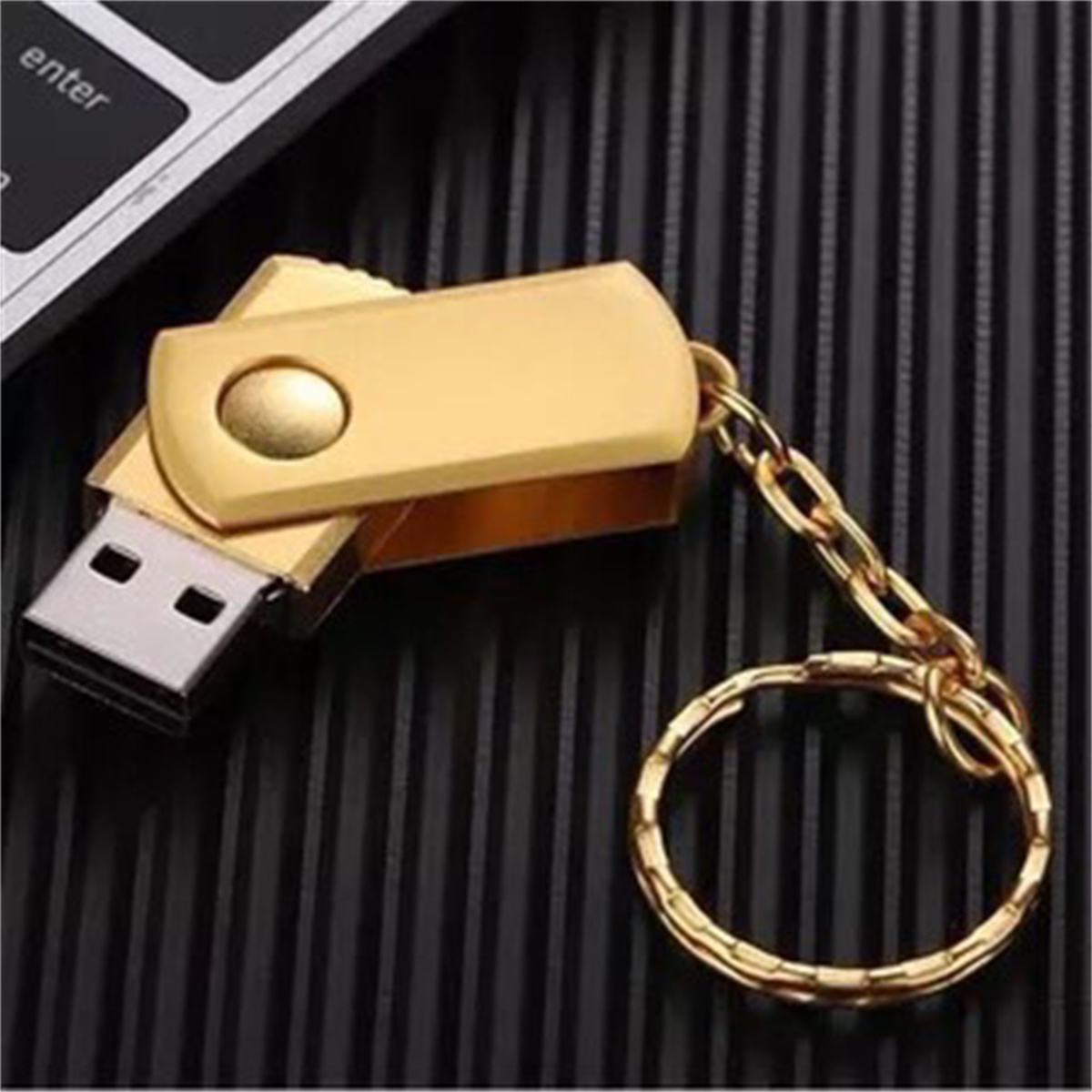 Ein goldener USB-Stick, befestigt an einem Schlüsselanhänger mit goldenem Ring, auf schwarzer Oberfläche.