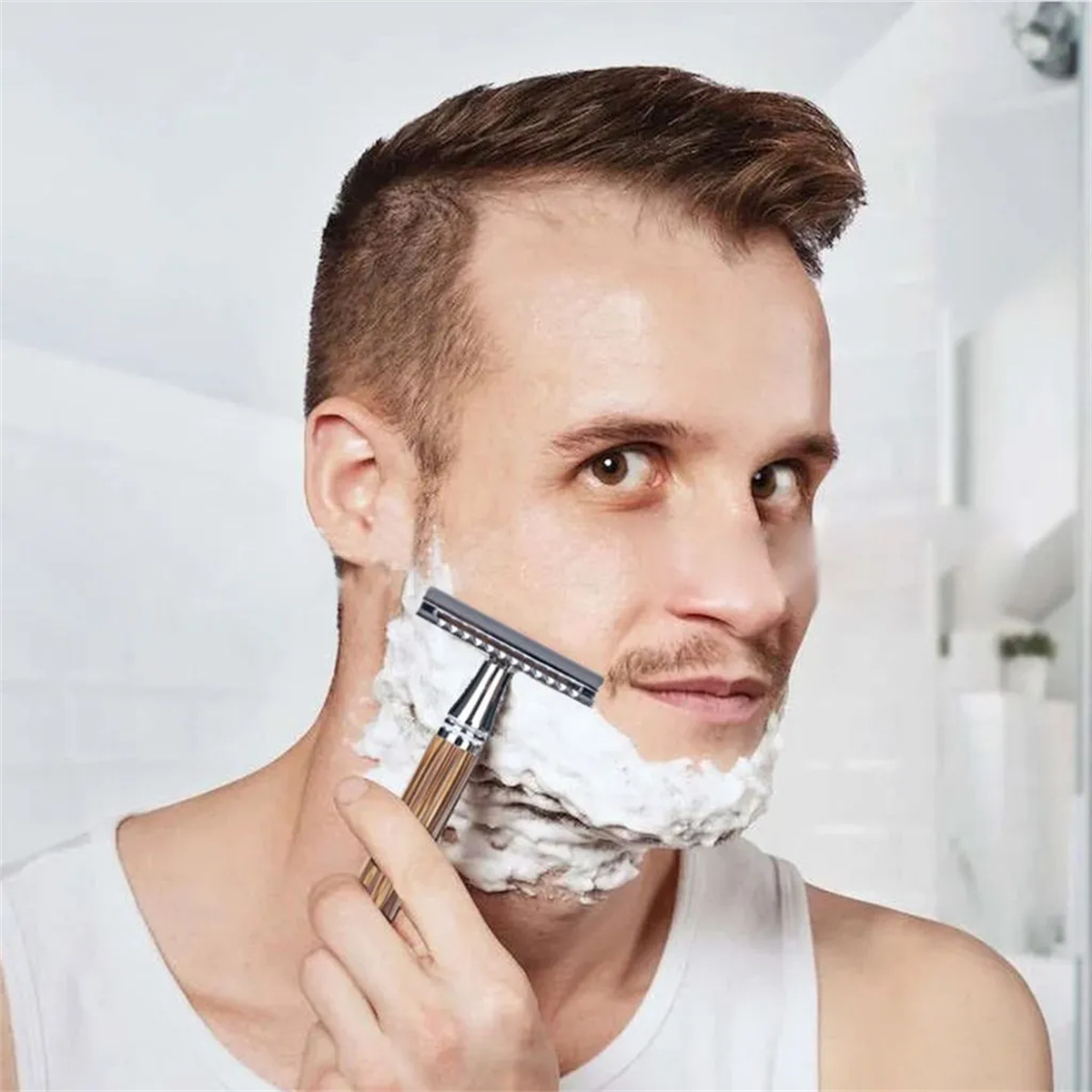 Mann rasiert sein Gesicht mit einem Rasierer und Rasierschaum. Weißer Hintergrund.