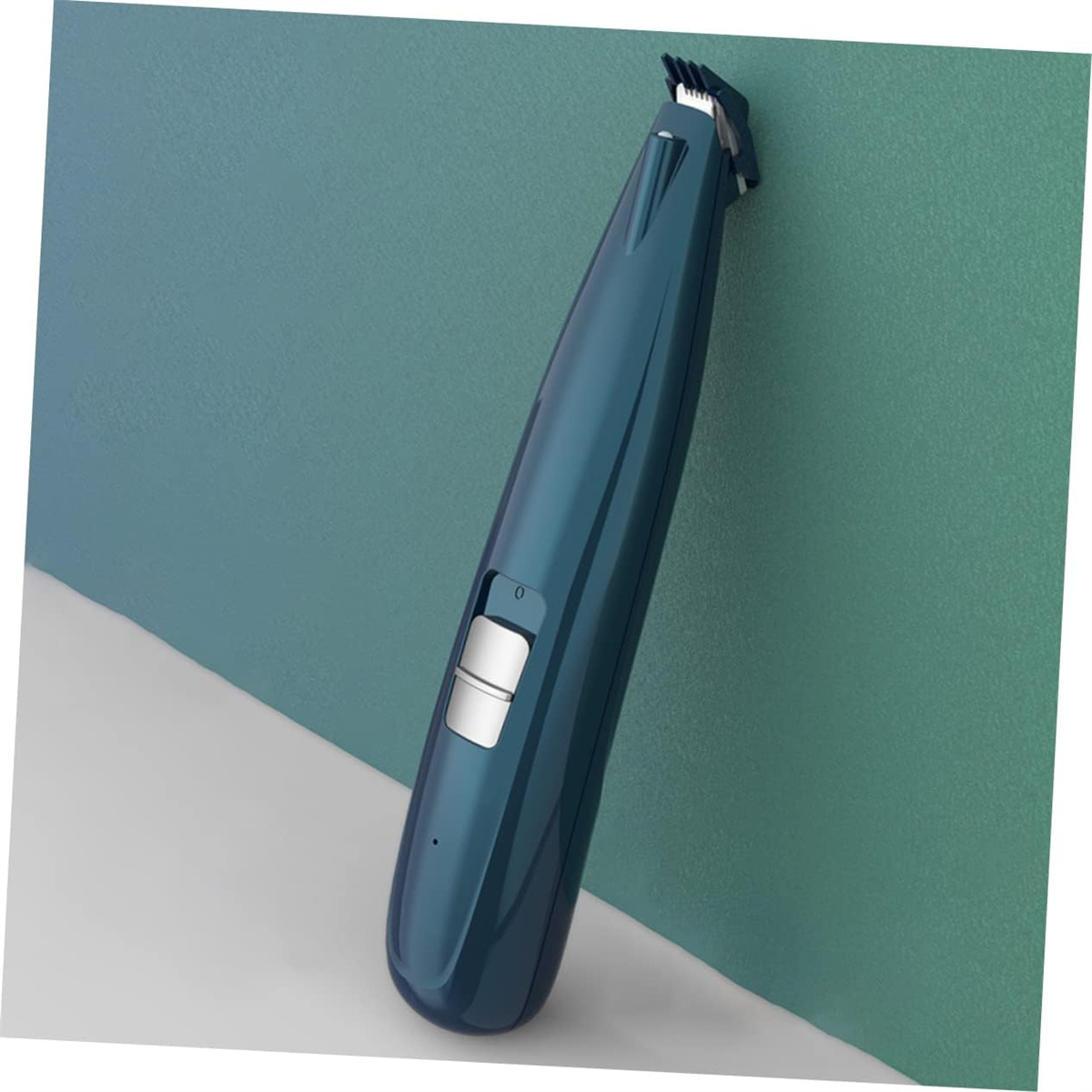 Ein blau-schwarzer Haarschneider auf einer weißen Oberfläche, abgewinkelt an einer türkisgrünen Wand.