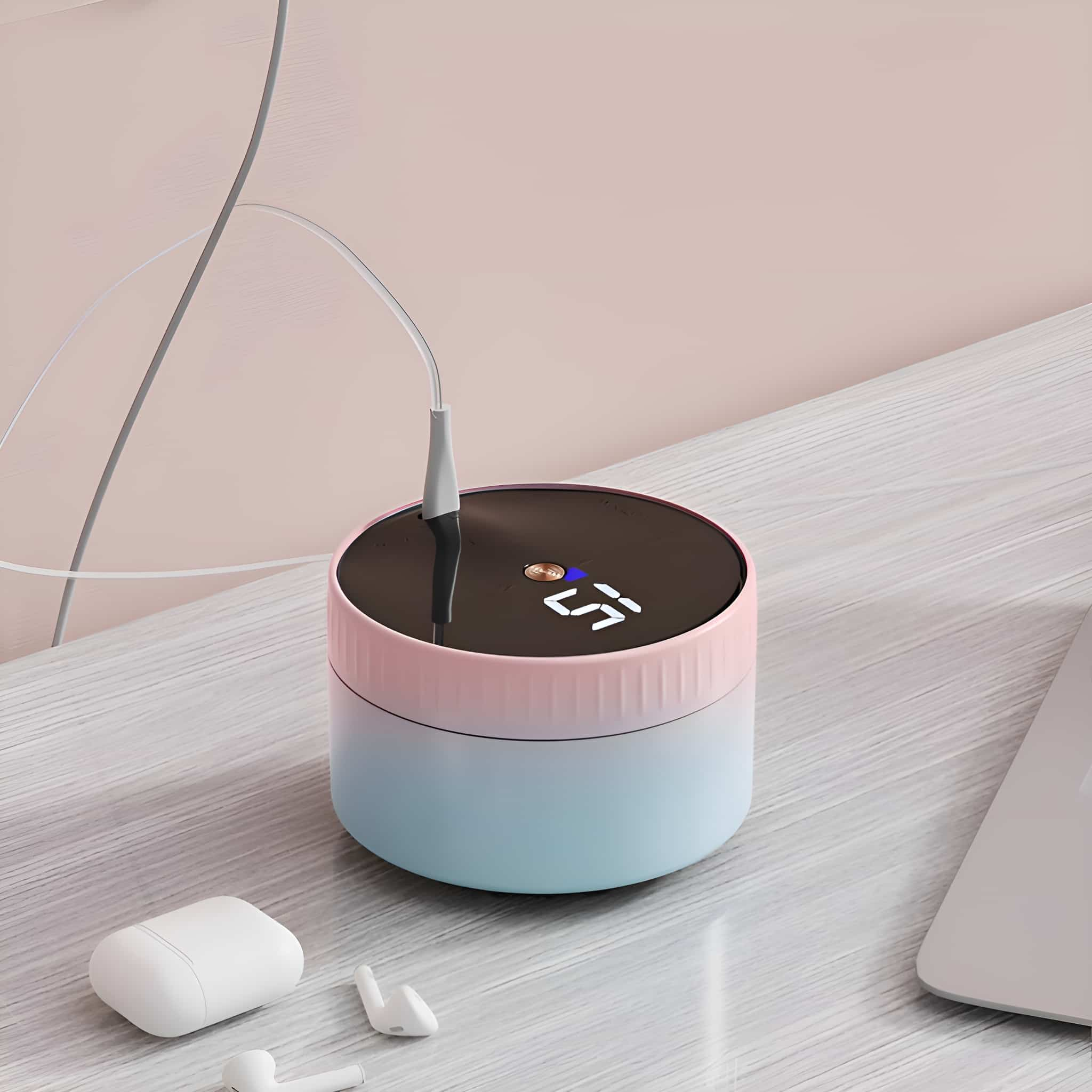 Rosa-blaues Ladegerät mit Digitalanzeige, mit Ohrhörern und Ladekabel in der Nähe.