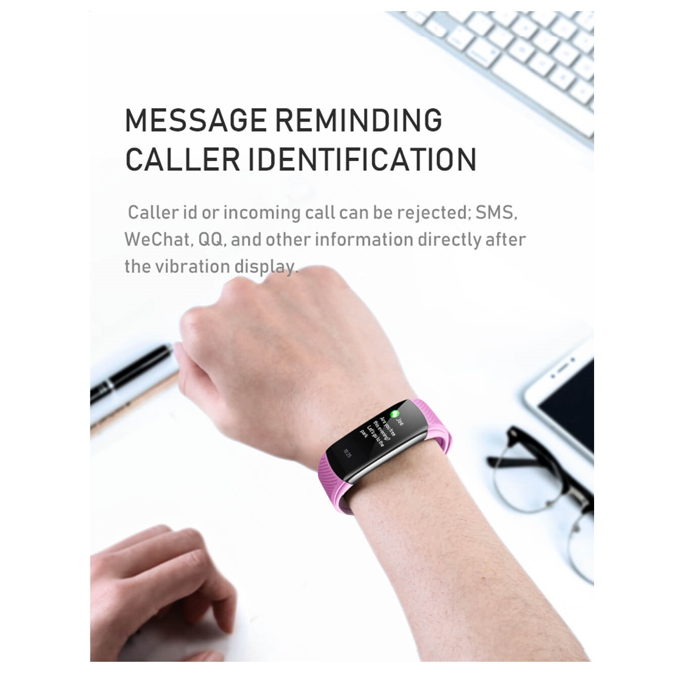 Różowa inteligentna bransoletka na nadgarstku wyświetlająca wiadomość, z telefonem i klawiaturą w tle.