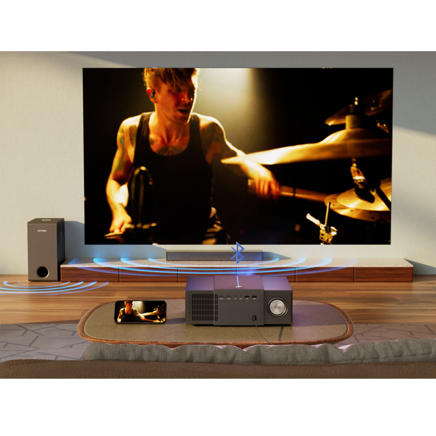 Projektor auf einem Tisch, der ein Bild einer Band auf einer großen Leinwand projiziert. Soundbar und Subwoofer.