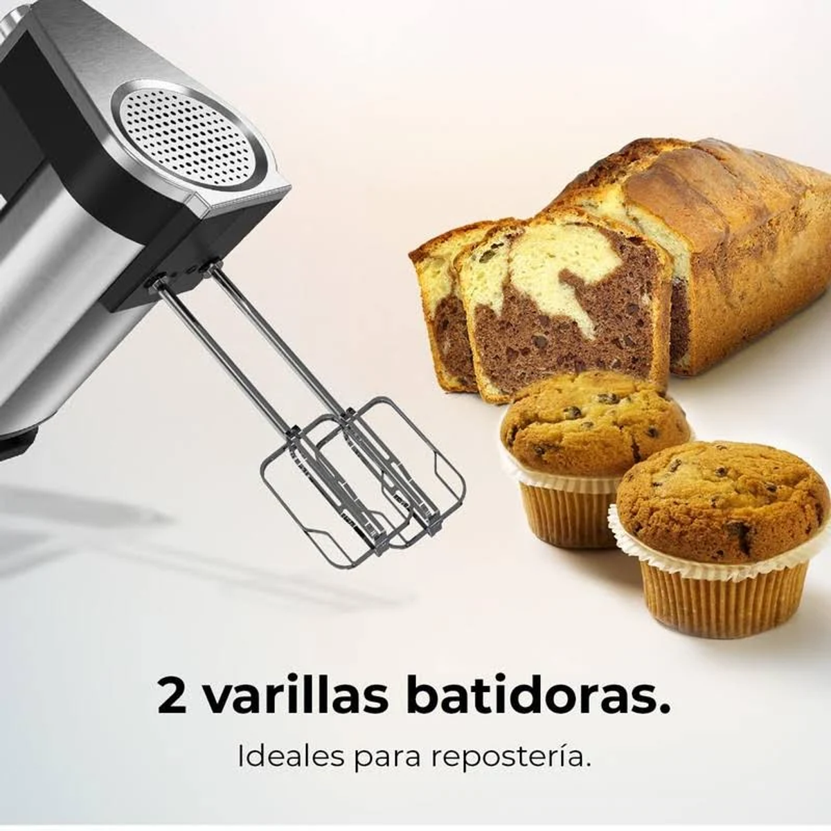 Frullatore a mano con fruste, accanto a pane a fette e muffin su sfondo chiaro.