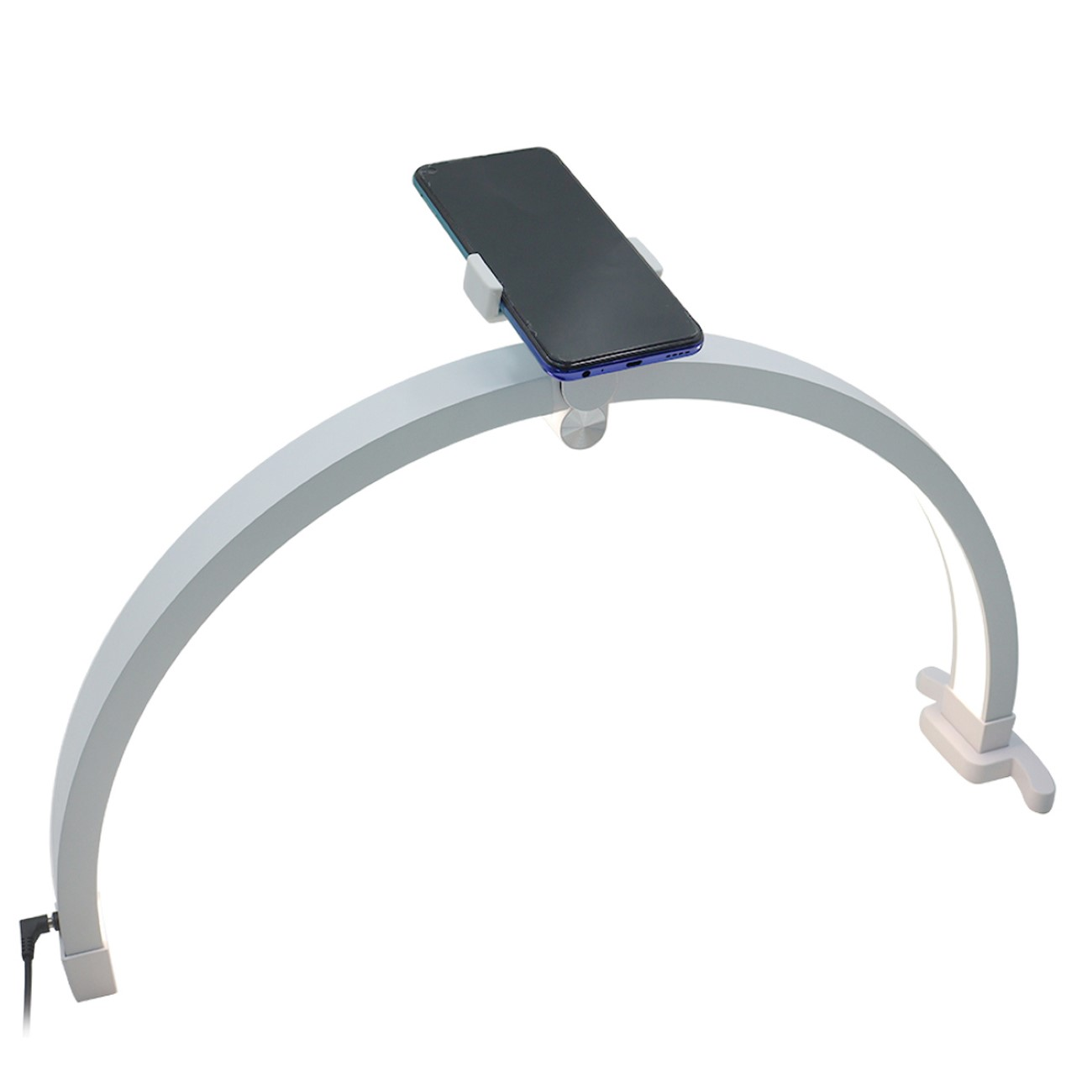 Eine weiße bogenförmige Lampe mit einer Telefonhalterung, die ein Smartphone hält.