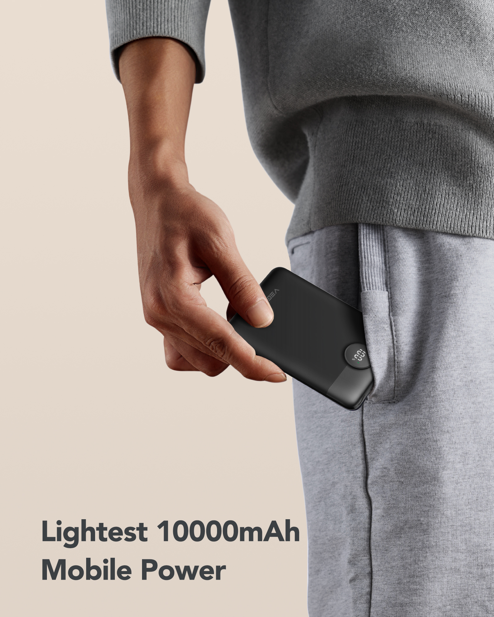 Person hält eine schwarze Powerbank in einer Tasche. Graue Jogginghose, Text darunter.