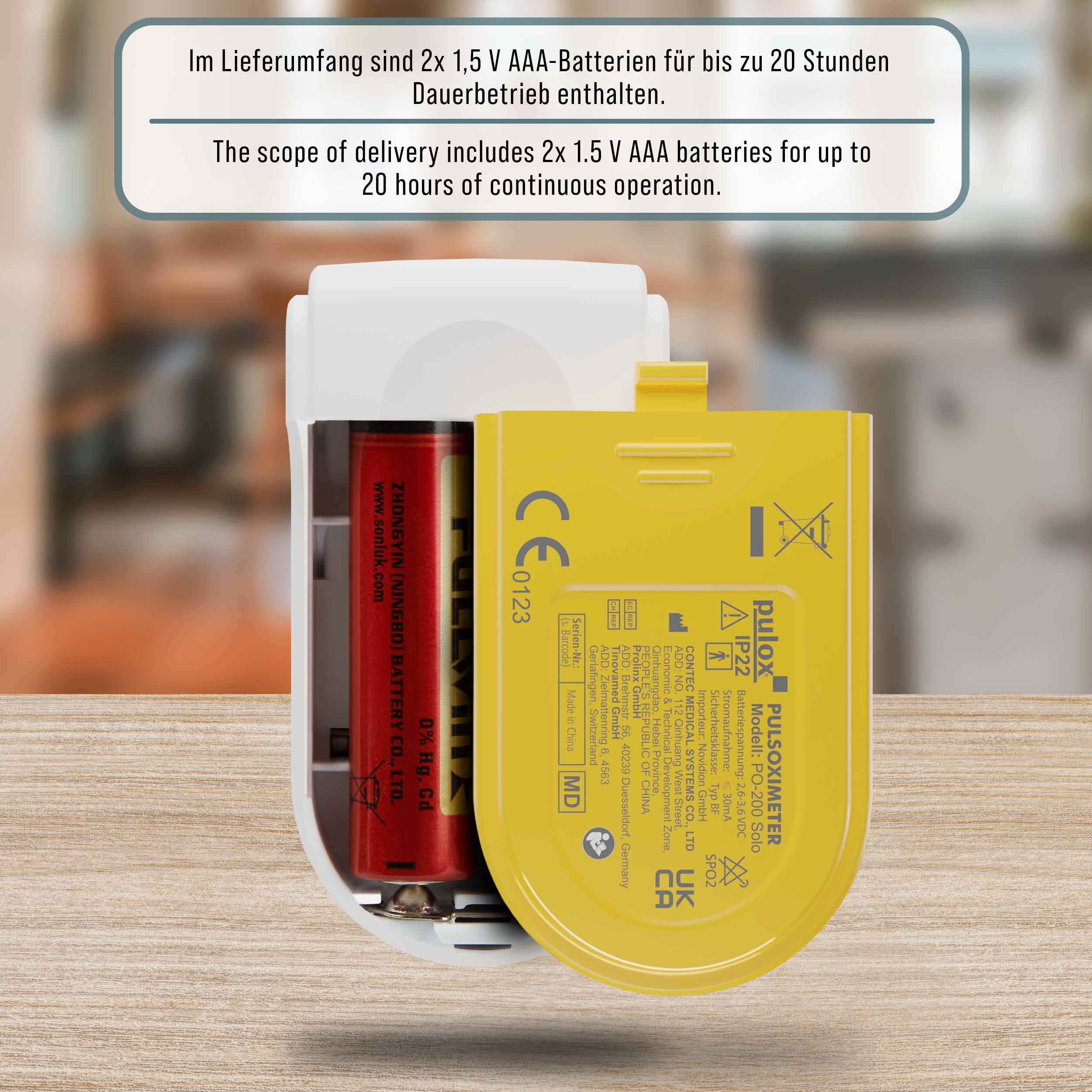 Ein medizinisches Gerät mit geöffnetem gelbem Batteriefach. Zwei AAA-Batterien sind innen, mit Text.