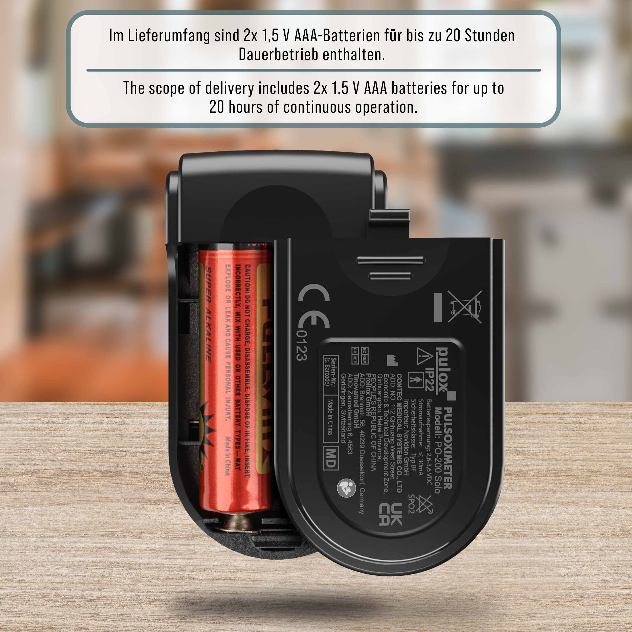 Geöffnetes schwarzes Pulsoximeter mit roter Batterie, Text auf Gerät und Batterie.