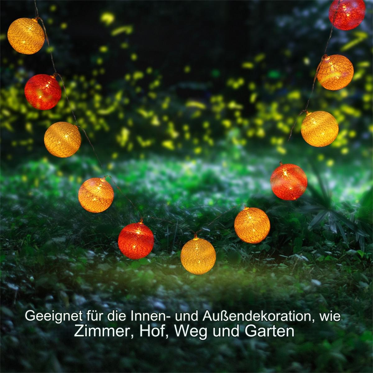 Kette aus orangefarbenen und roten Kugellampen im Garten mit Gras.